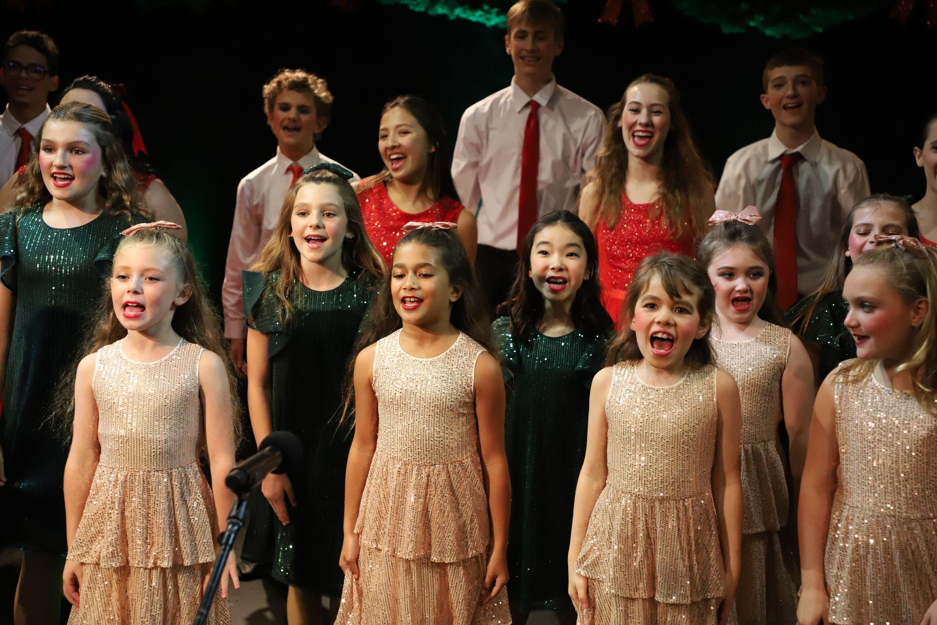 A group of children are singing together on a stage.