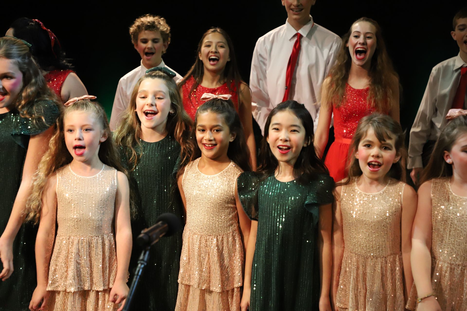 A group of children are singing together on a stage.