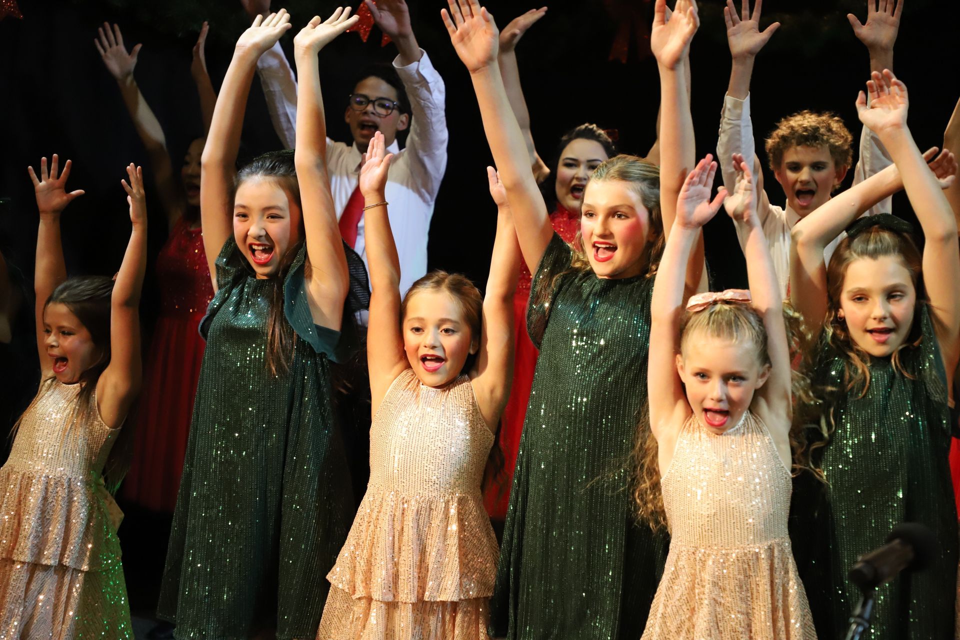 A group of young girls are raising their arms in the air.