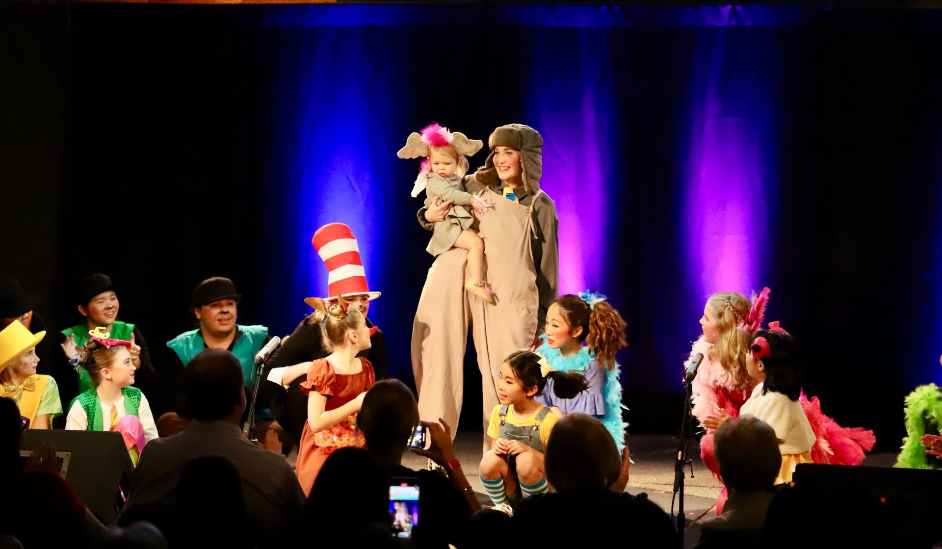 A group of people in costumes are standing on a stage.