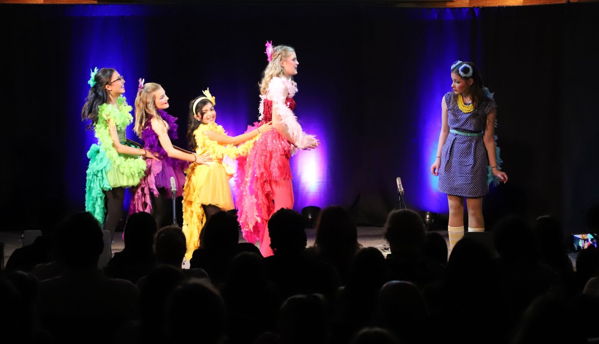 A group of girls are dancing on a stage in front of a crowd.