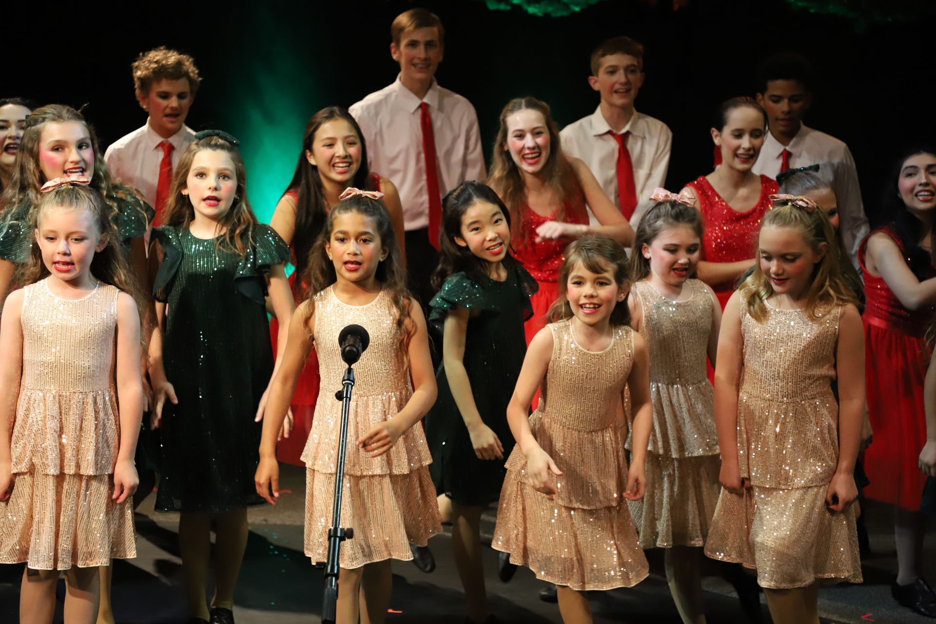 A group of young girls are singing into a microphone on a stage.