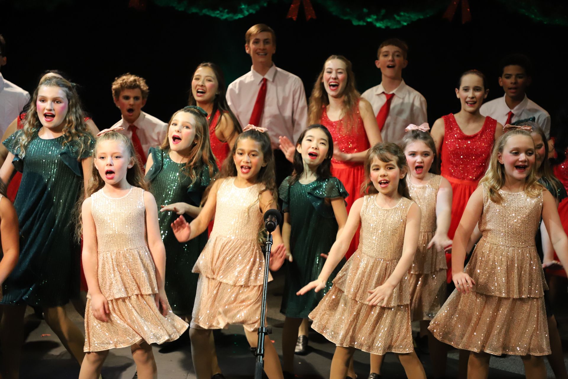 A group of children are singing and dancing on a stage.