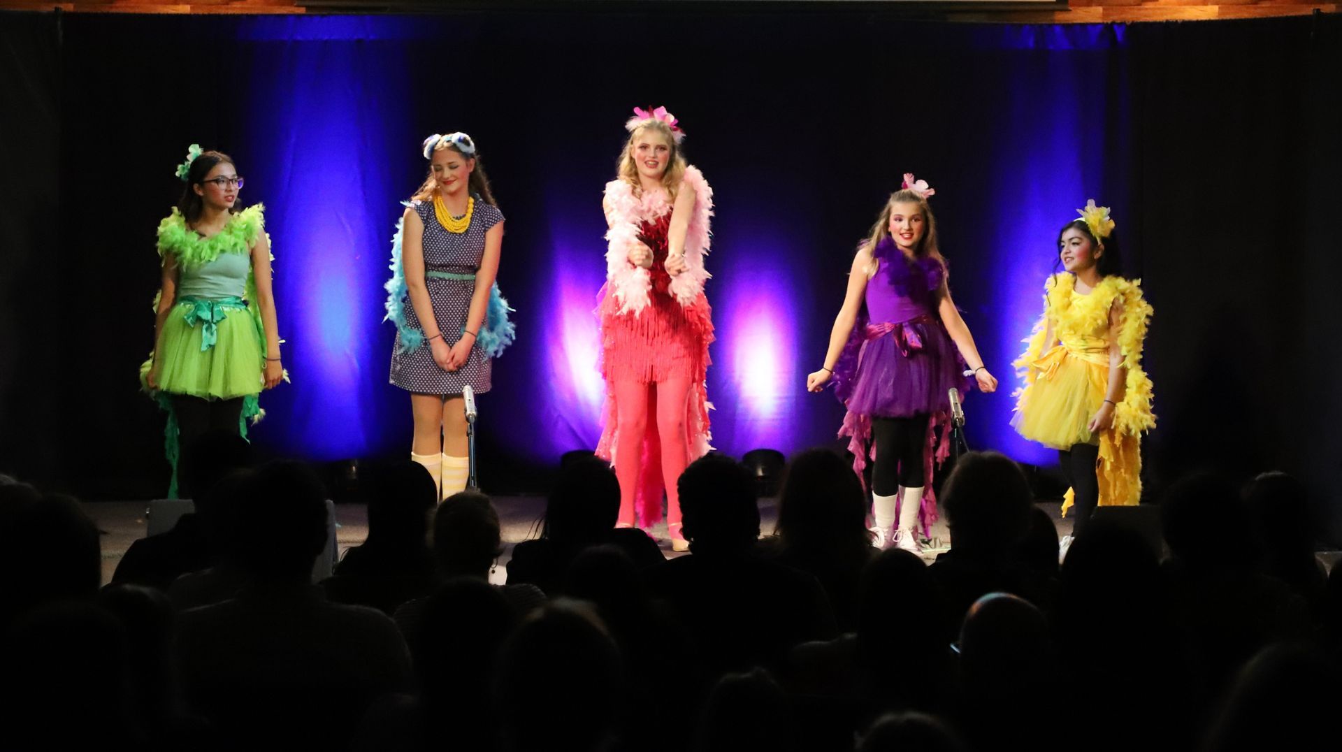 A group of girls are standing on a stage in front of a crowd.