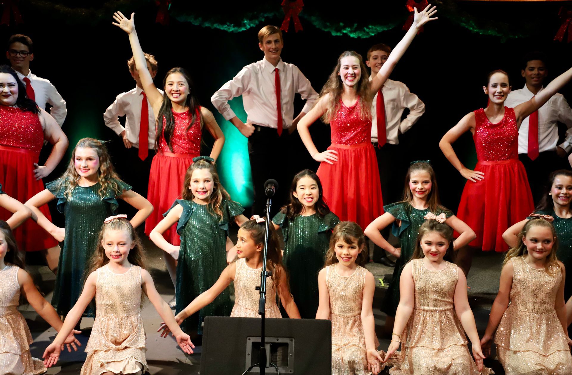 A group of young girls are dancing on a stage in front of a microphone.