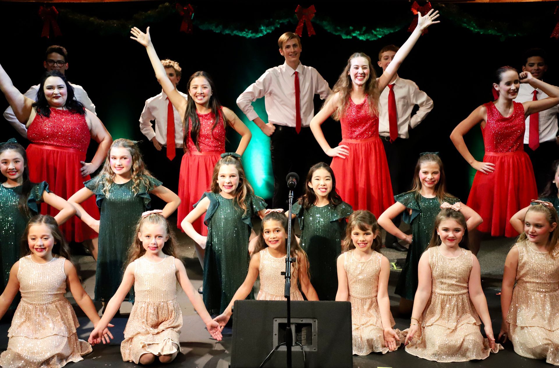 A group of young girls are dancing on a stage in front of a microphone.