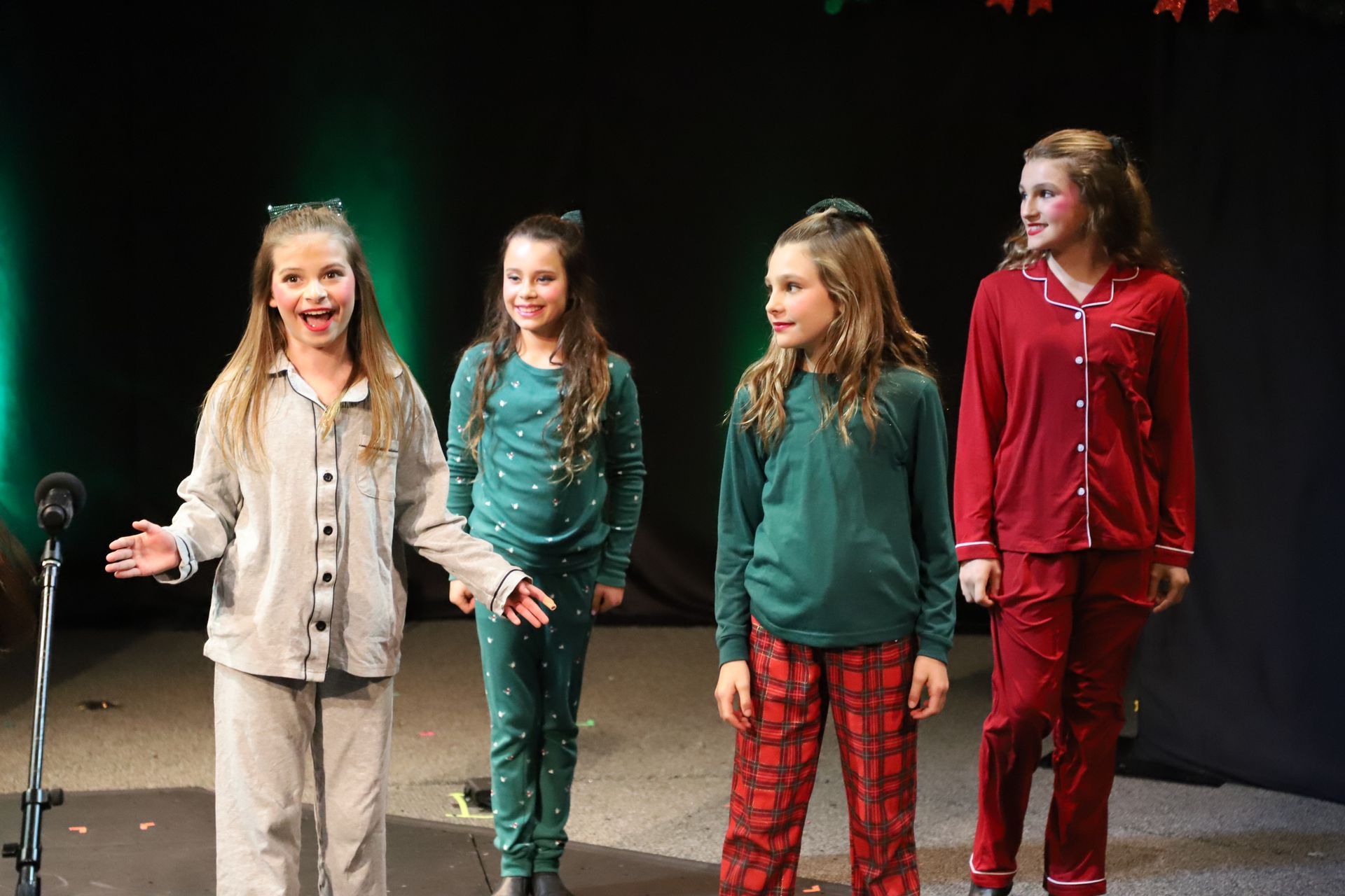 A group of young girls are standing in front of a microphone on a stage.