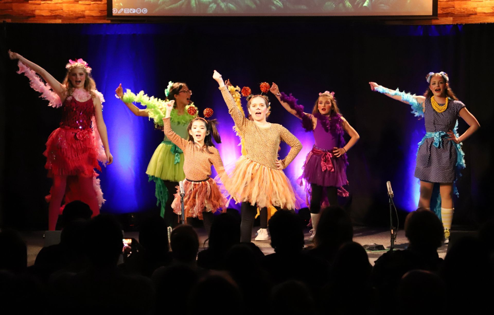 A group of young girls are dancing on a stage in front of a crowd.