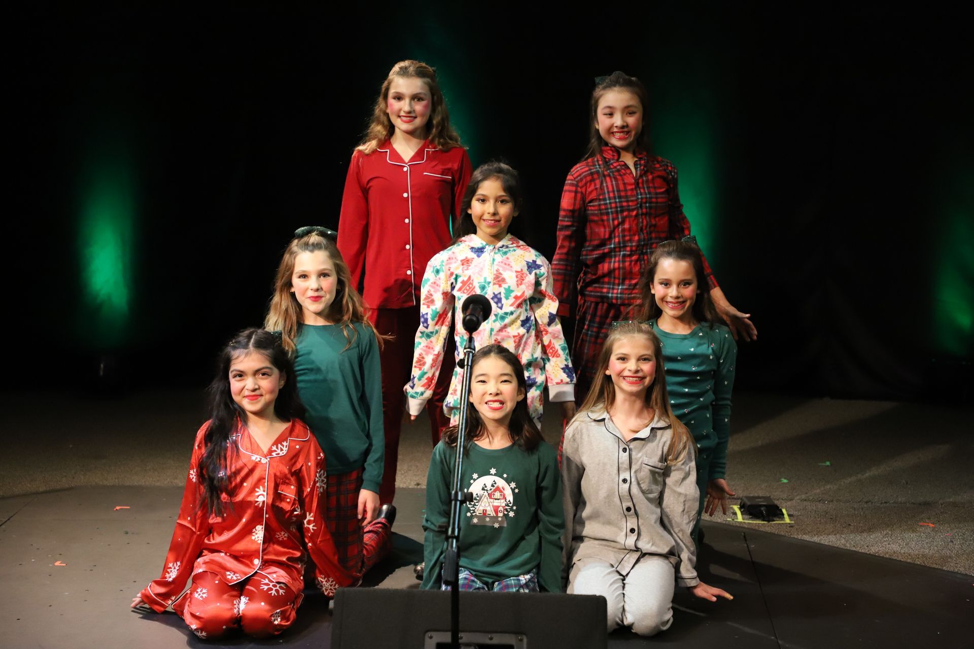A group of young girls are posing for a picture on a stage.