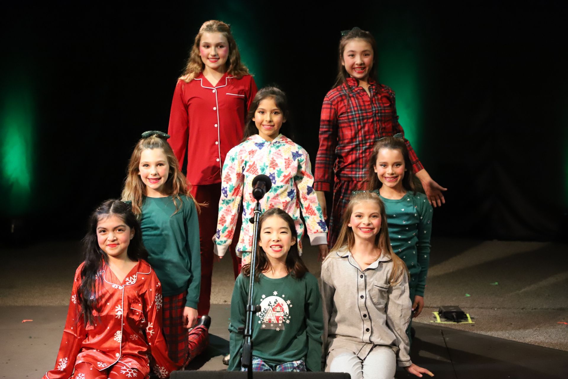A group of young girls are posing for a picture on a stage.