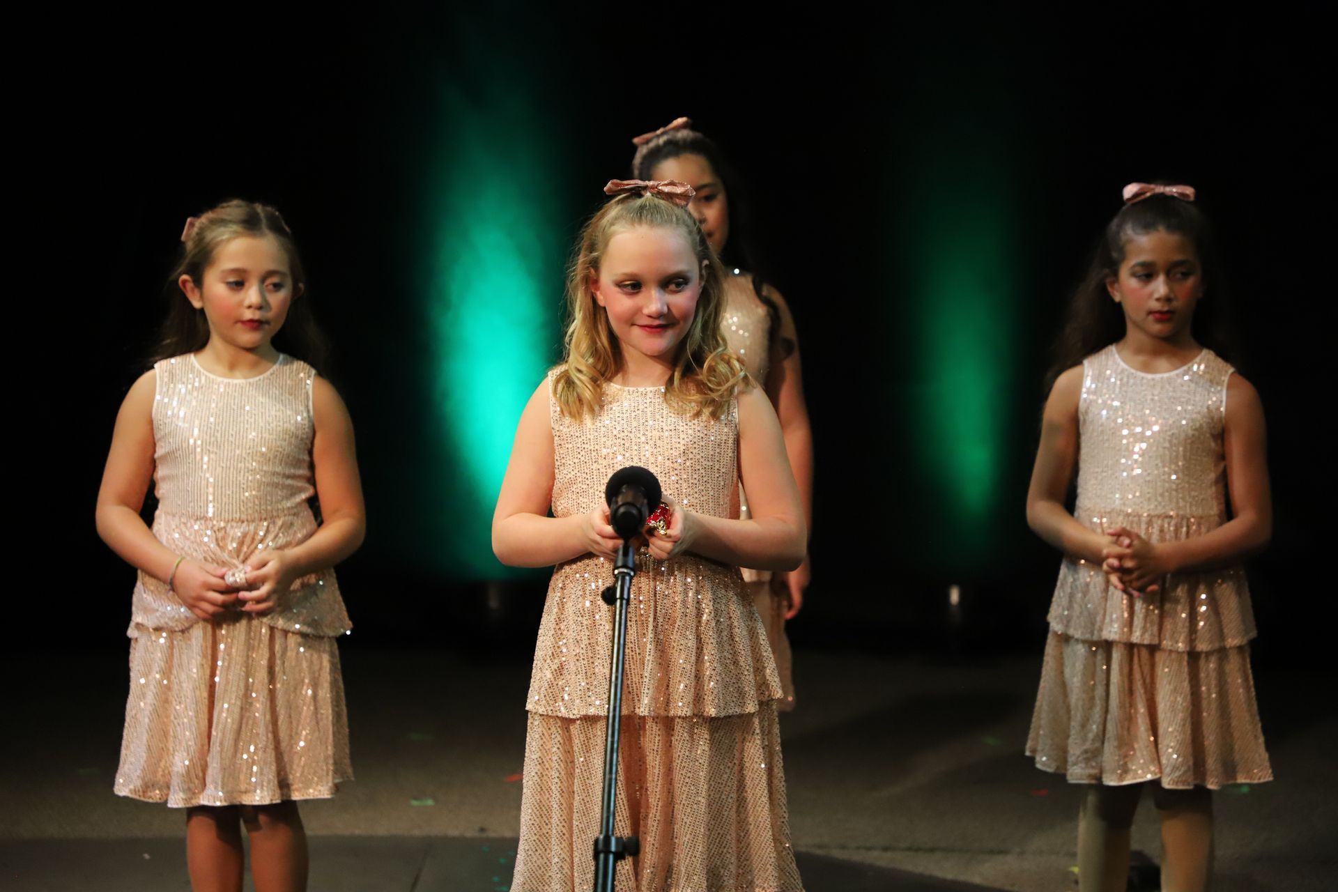 A group of young girls are singing into microphones on a stage.