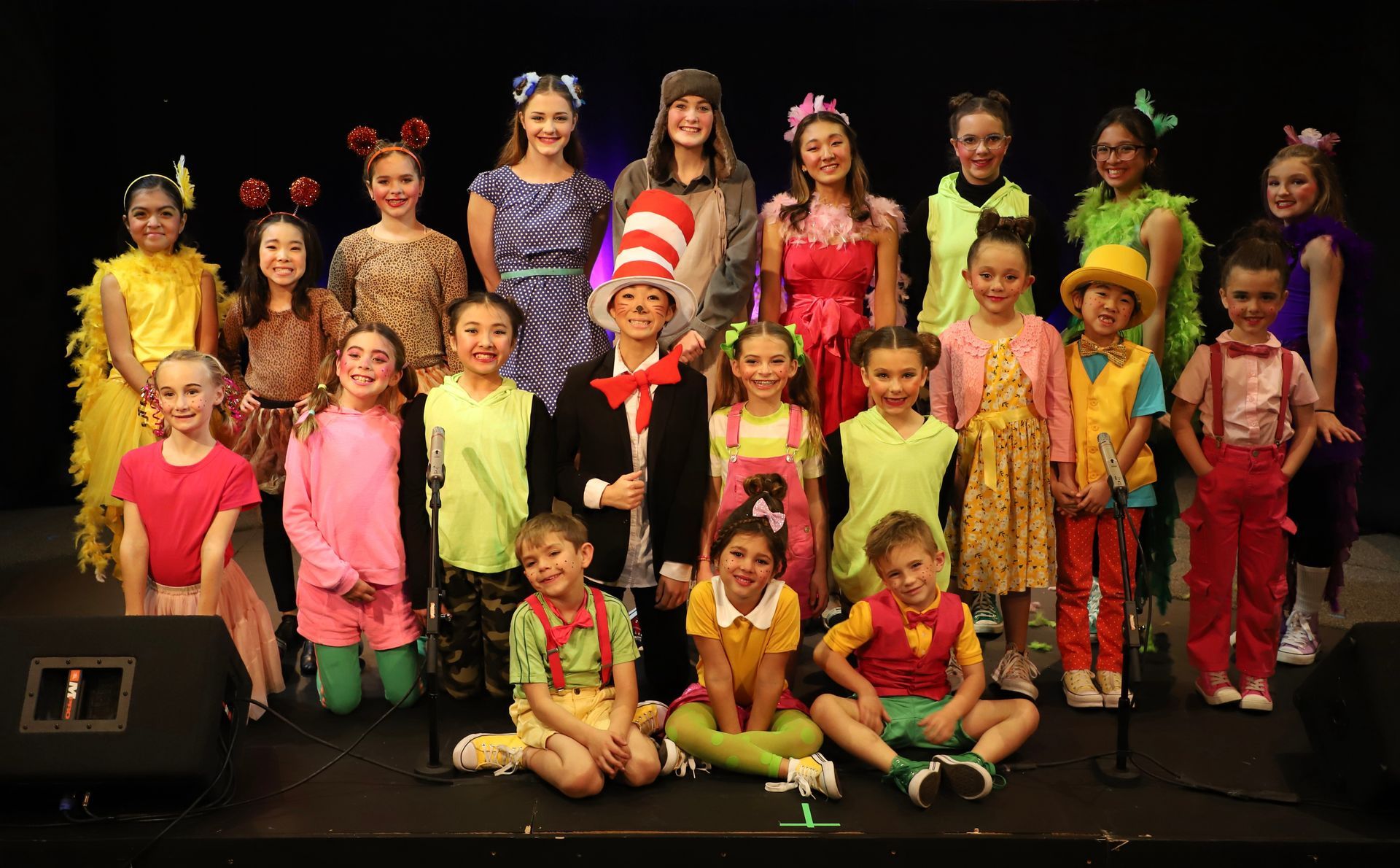 A group of children in costumes are posing for a picture on a stage.