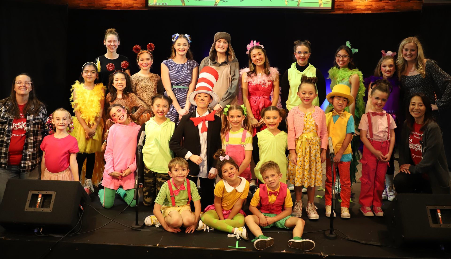 A group of children in costumes are posing for a picture on a stage.