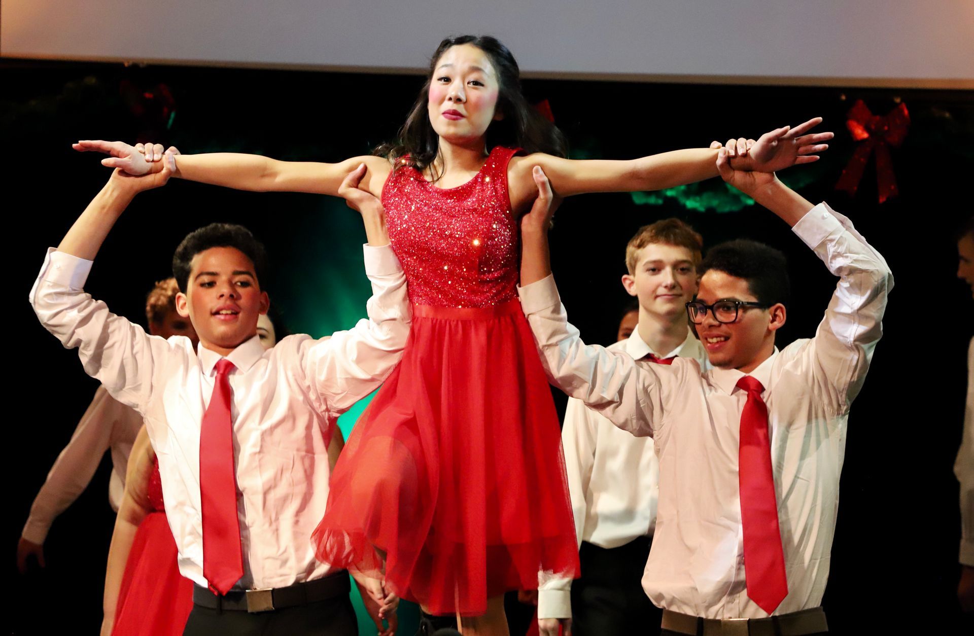 A group of young men are holding a woman in a red dress over their heads.