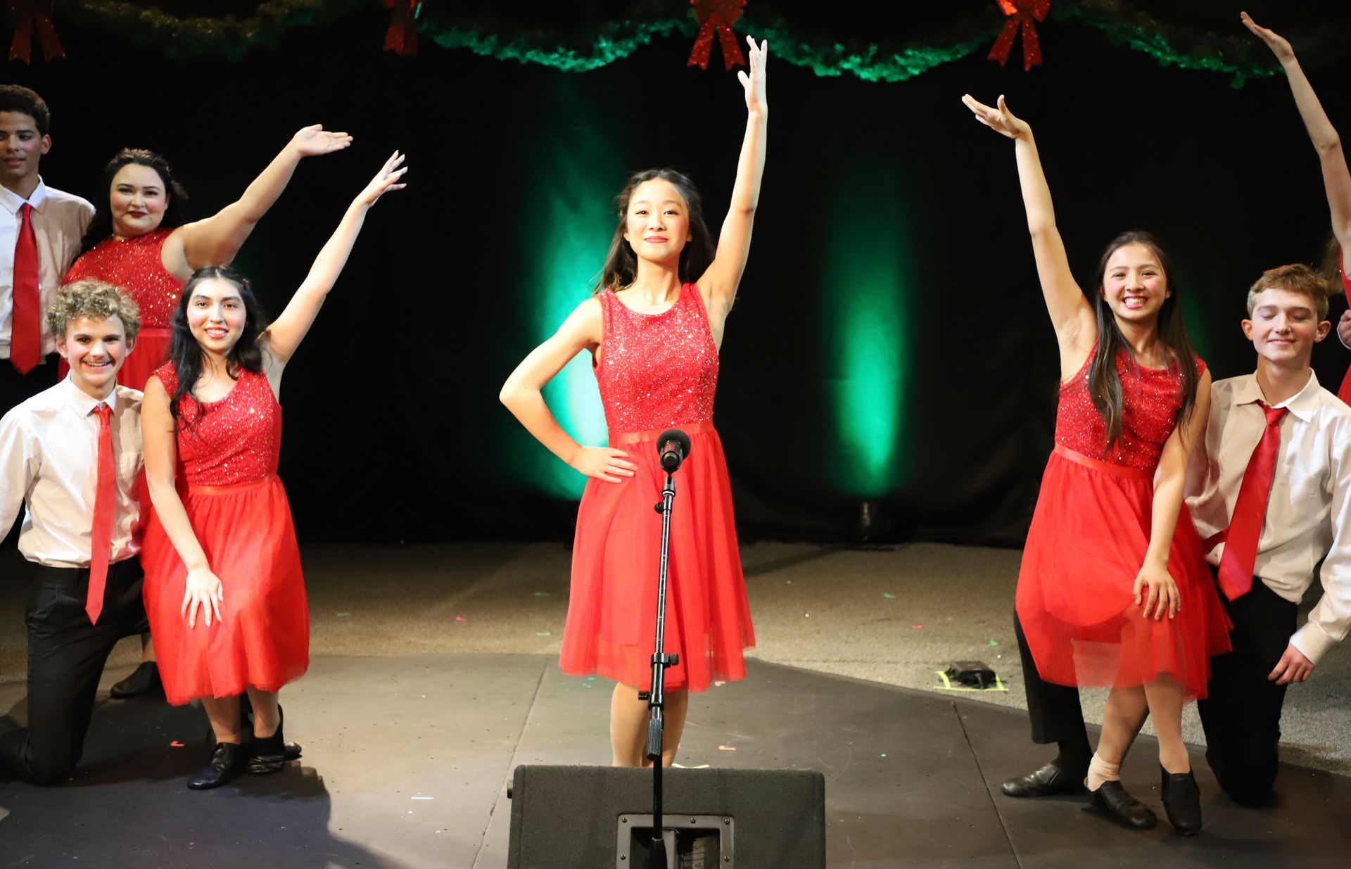A group of people are standing on a stage with their arms in the air.