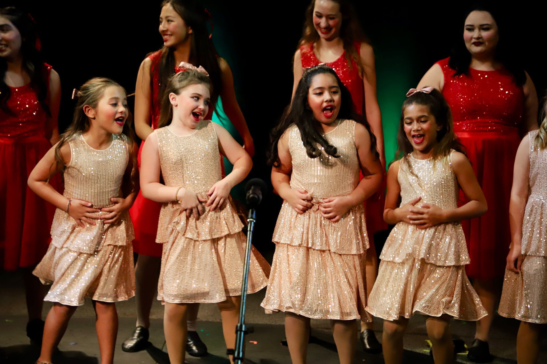 A group of young girls are singing into microphones on a stage.