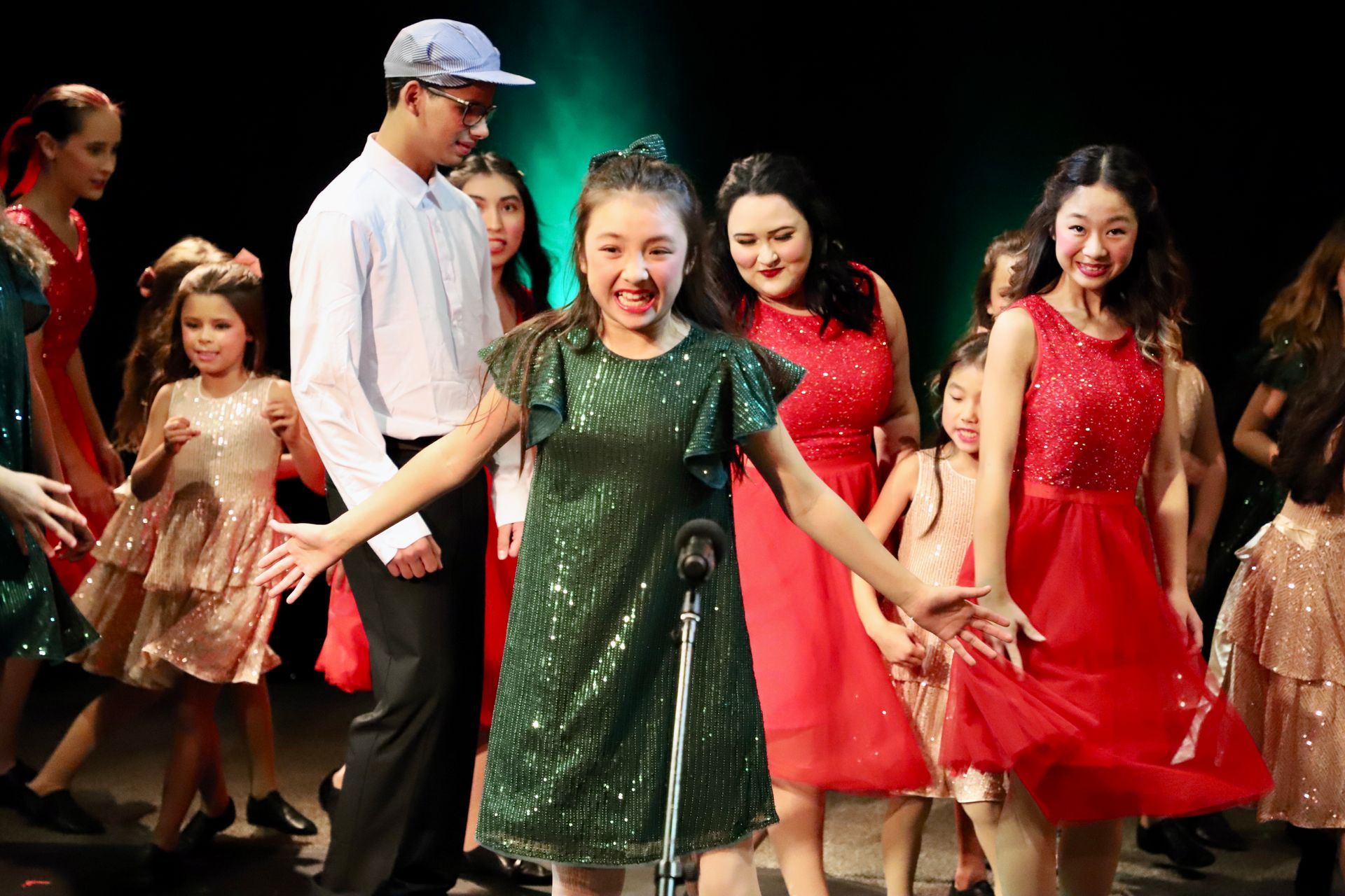 A group of children are standing on a stage holding hands.