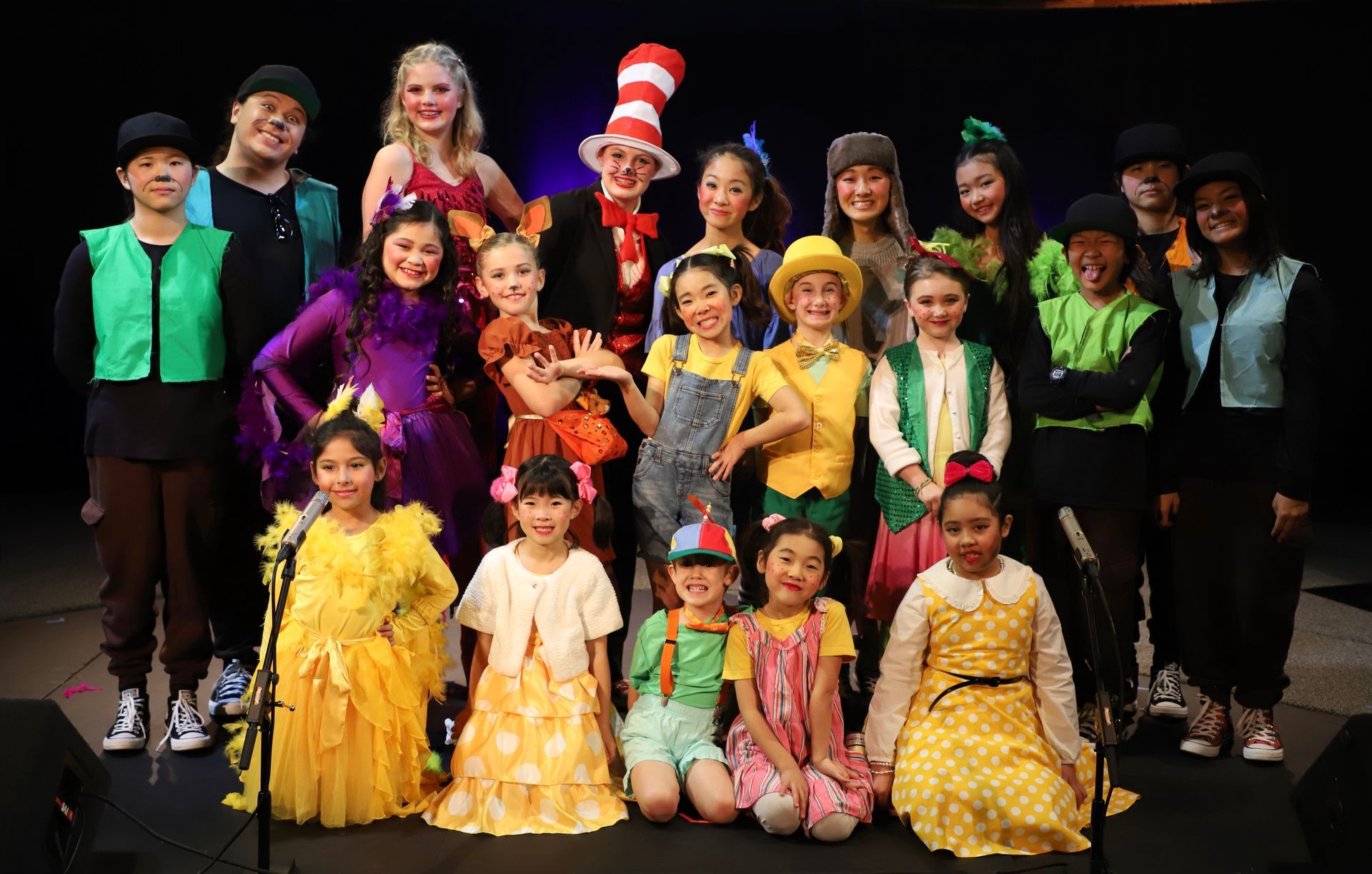 A group of children in costumes are posing for a picture on a stage.