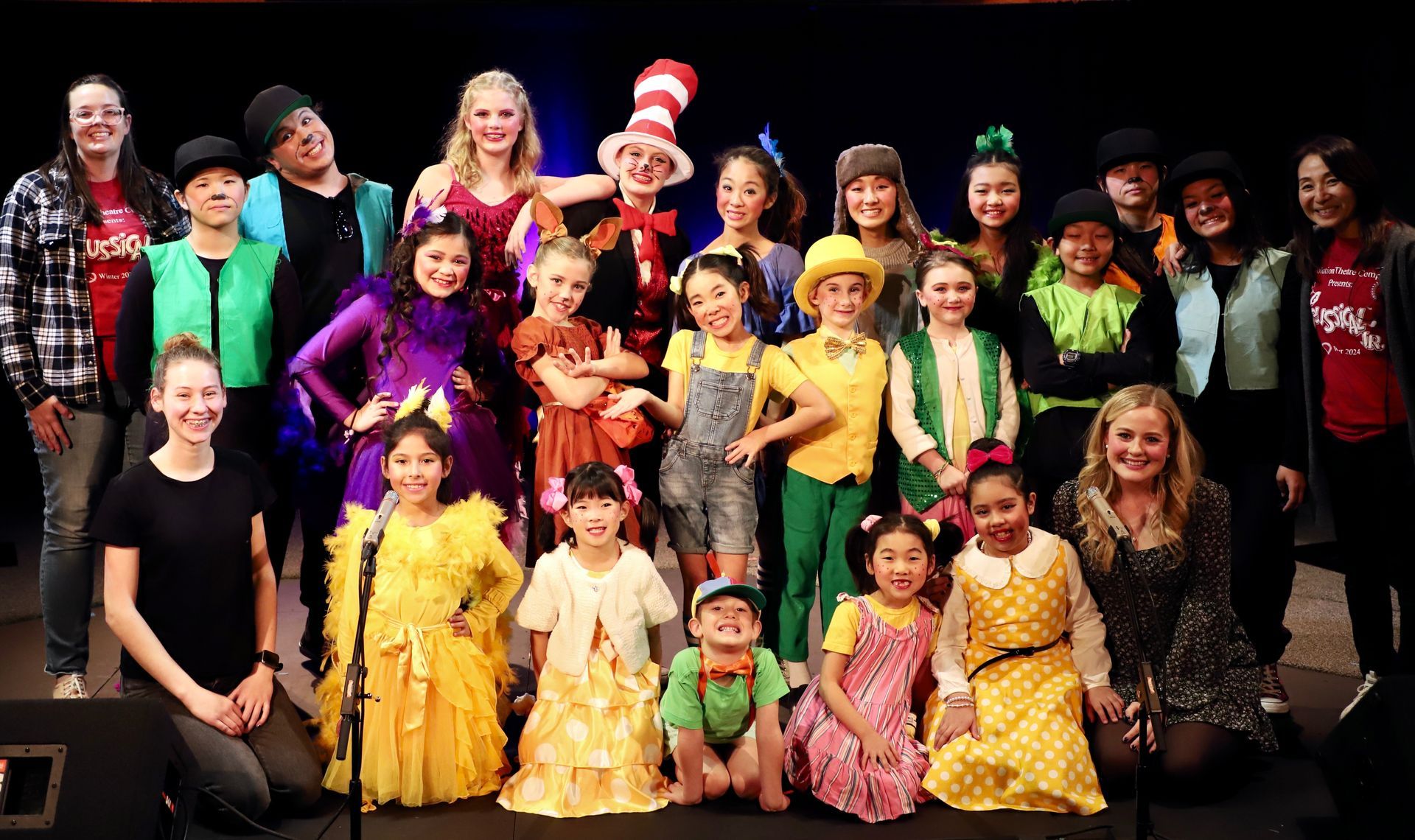 A group of children in costumes are posing for a picture on a stage.