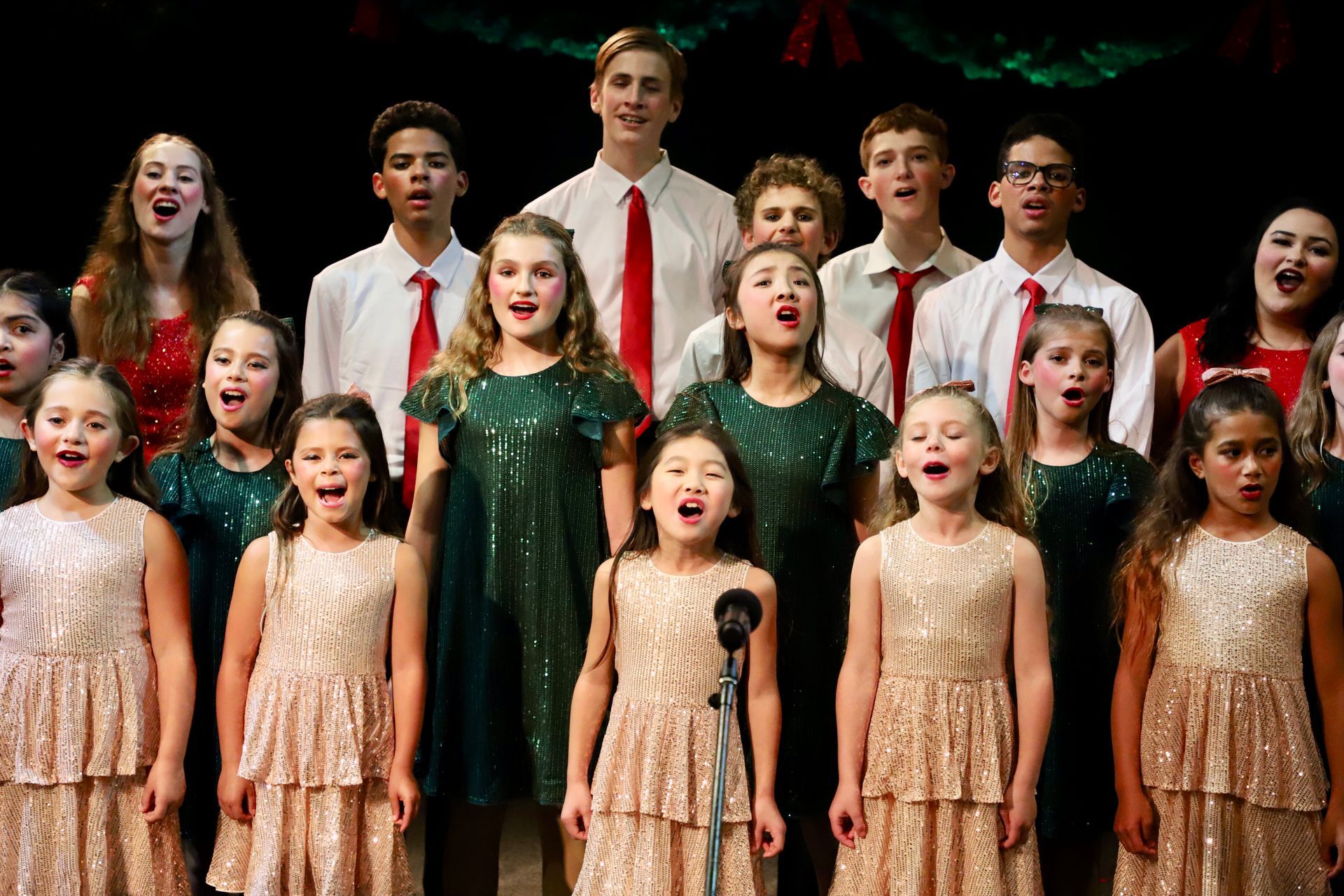 A group of children are singing in a choir on a stage.