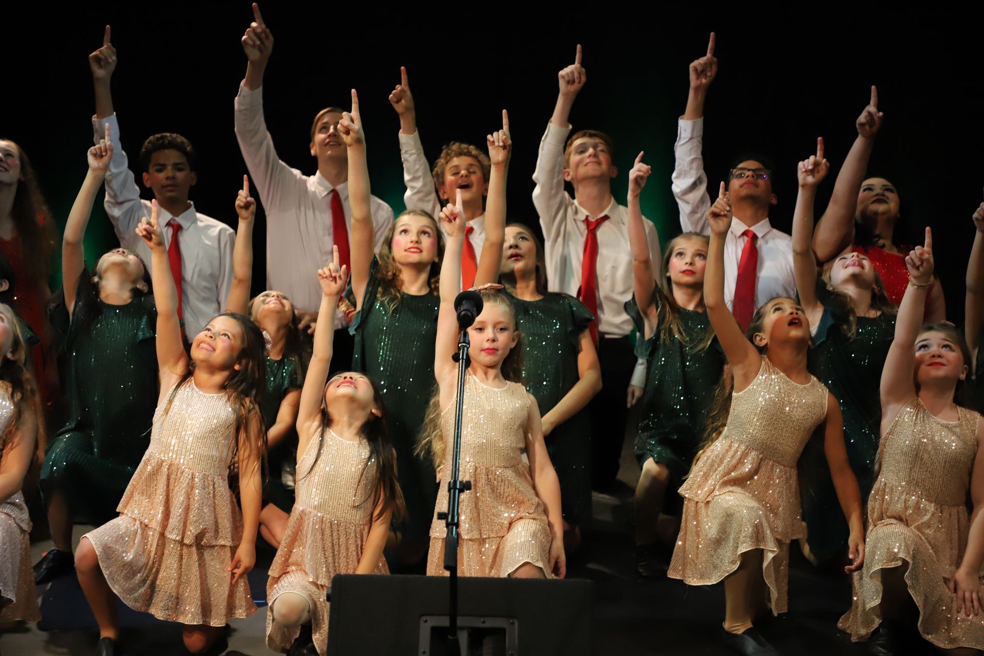 A group of young people are standing on a stage with their arms in the air.