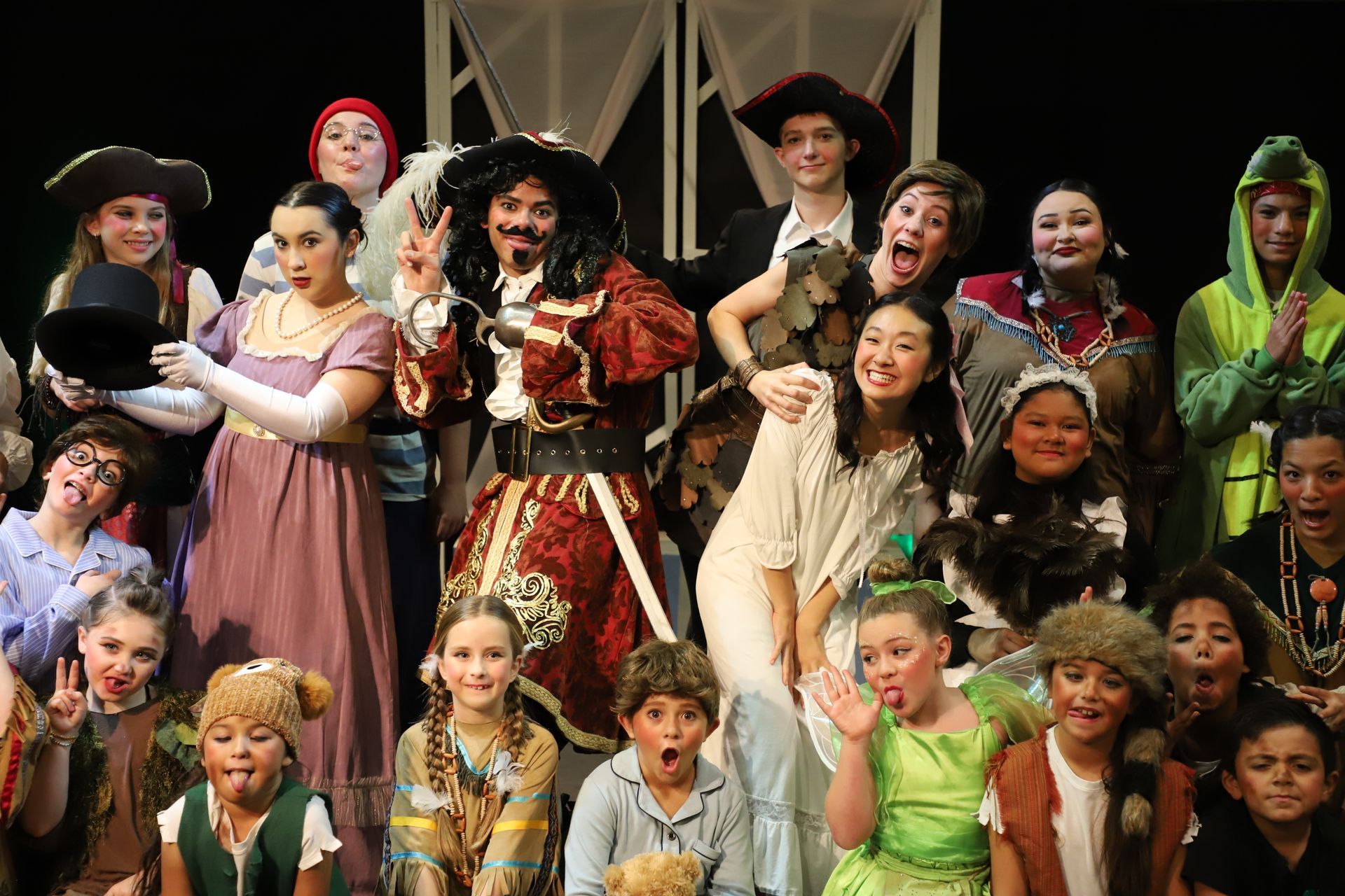 A group of children dressed in costumes are posing for a picture on a stage.
