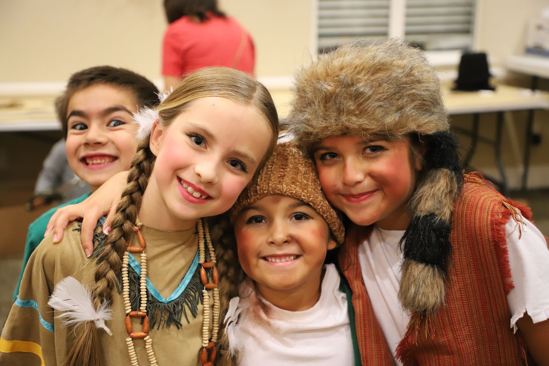 A group of young children dressed in native american costumes are posing for a picture.