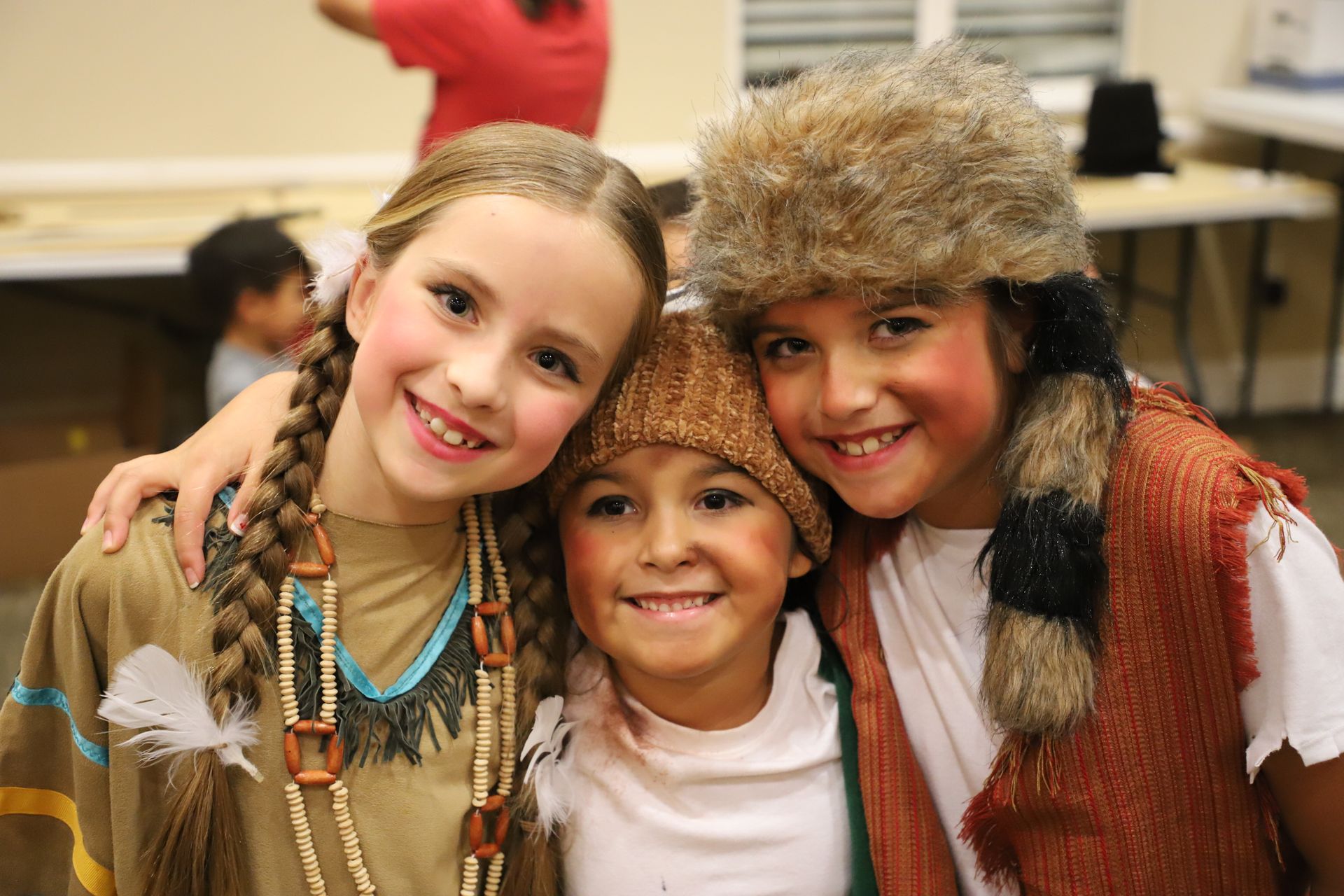 Three young girls dressed in native american costumes are posing for a picture.