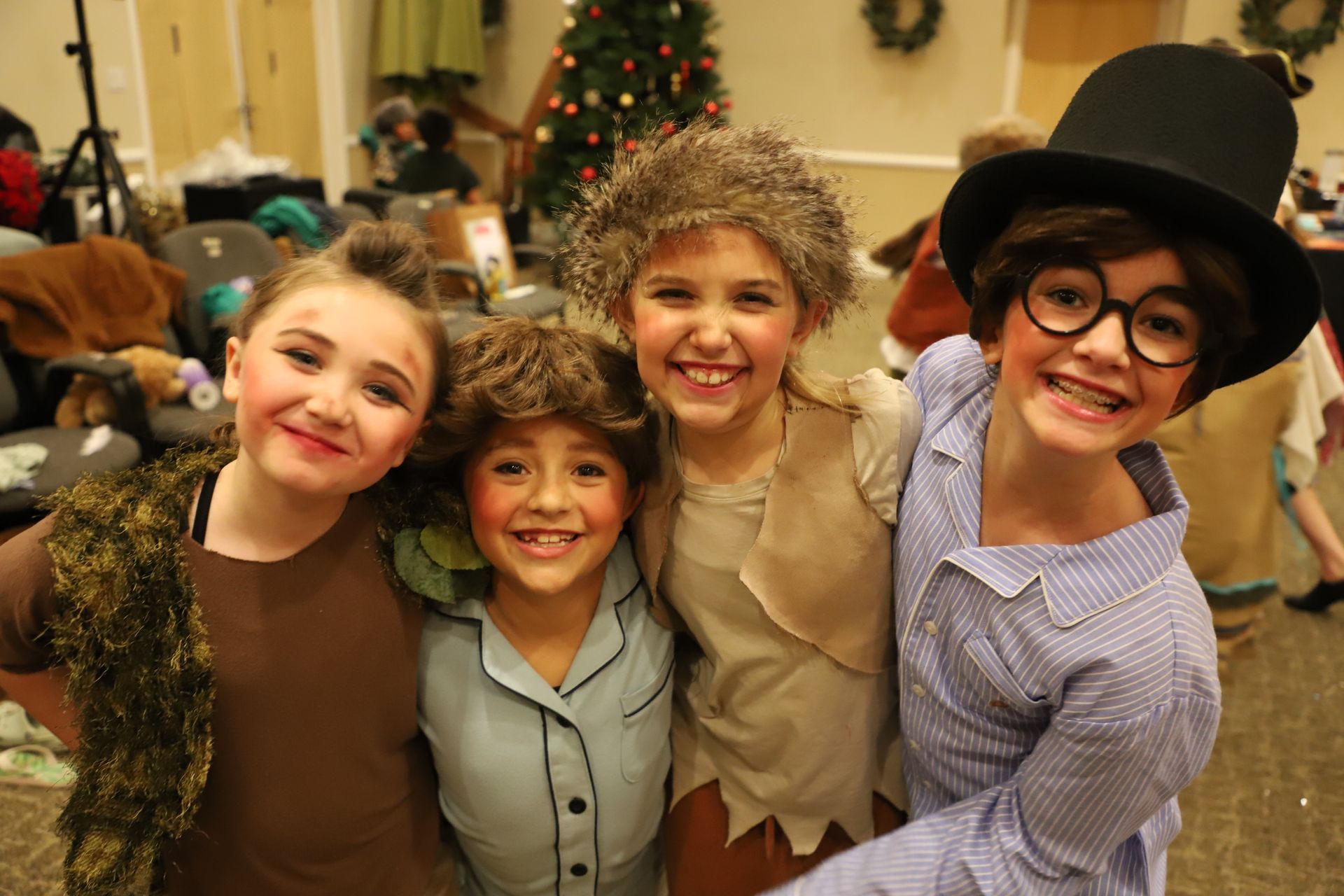 A group of children are posing for a picture in front of a christmas tree.