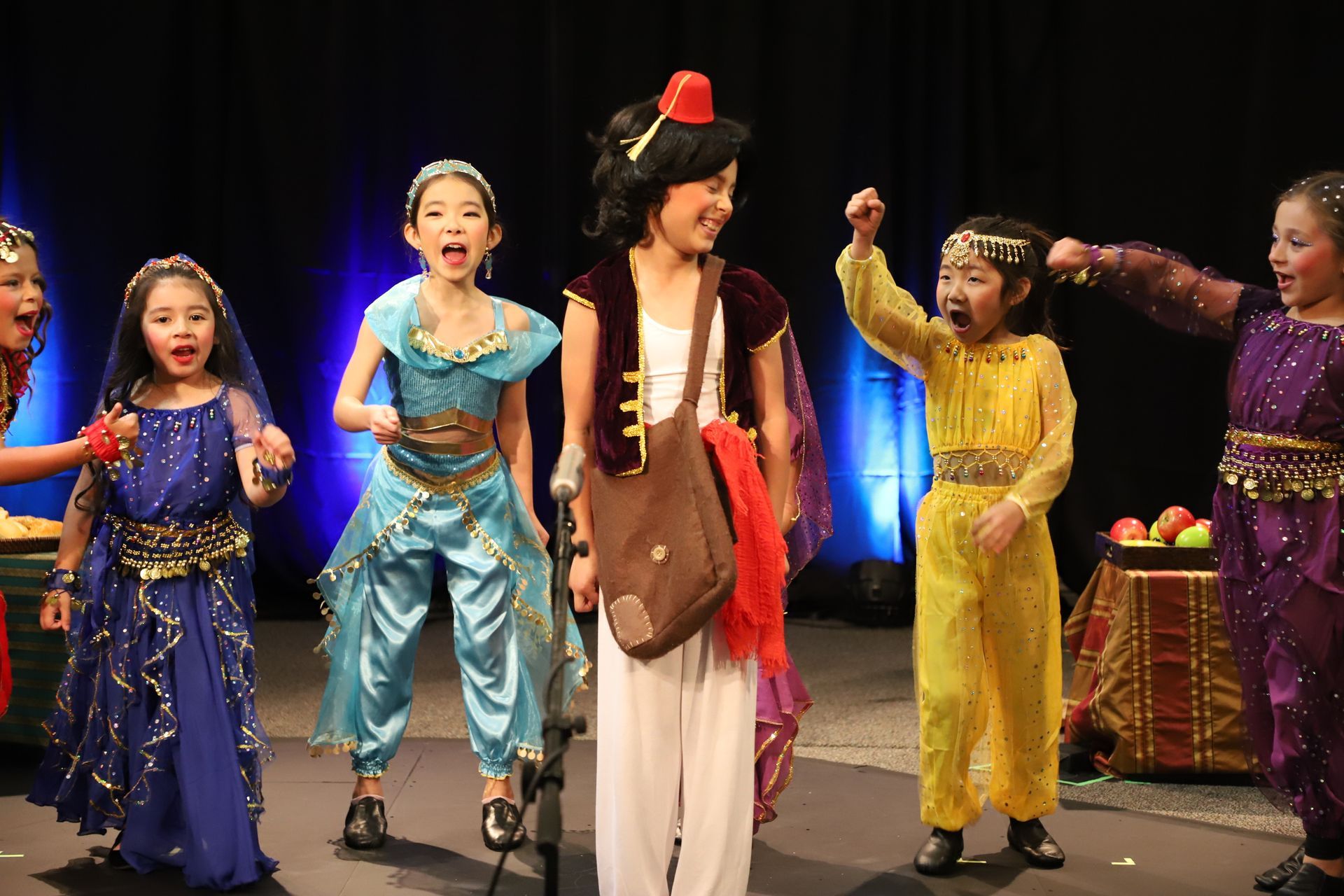 A group of children dressed in costumes are standing on a stage.