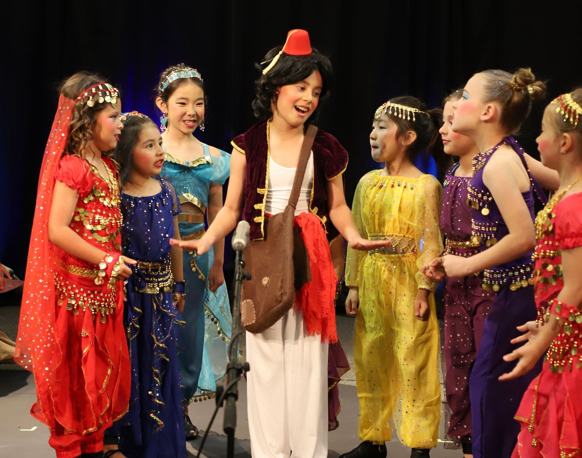 A group of young girls dressed in costumes are singing into microphones