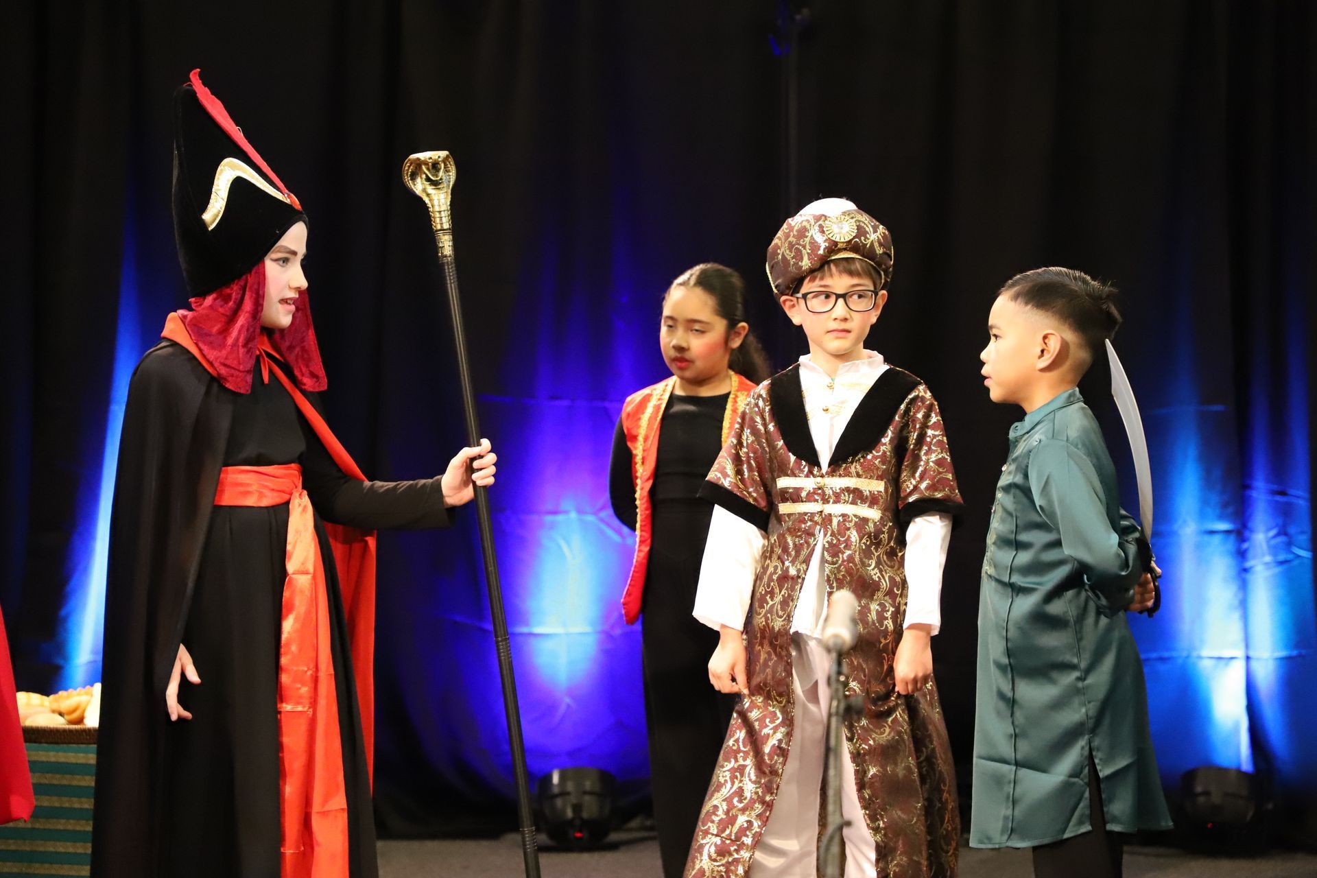 A group of children dressed in costumes are standing on a stage.