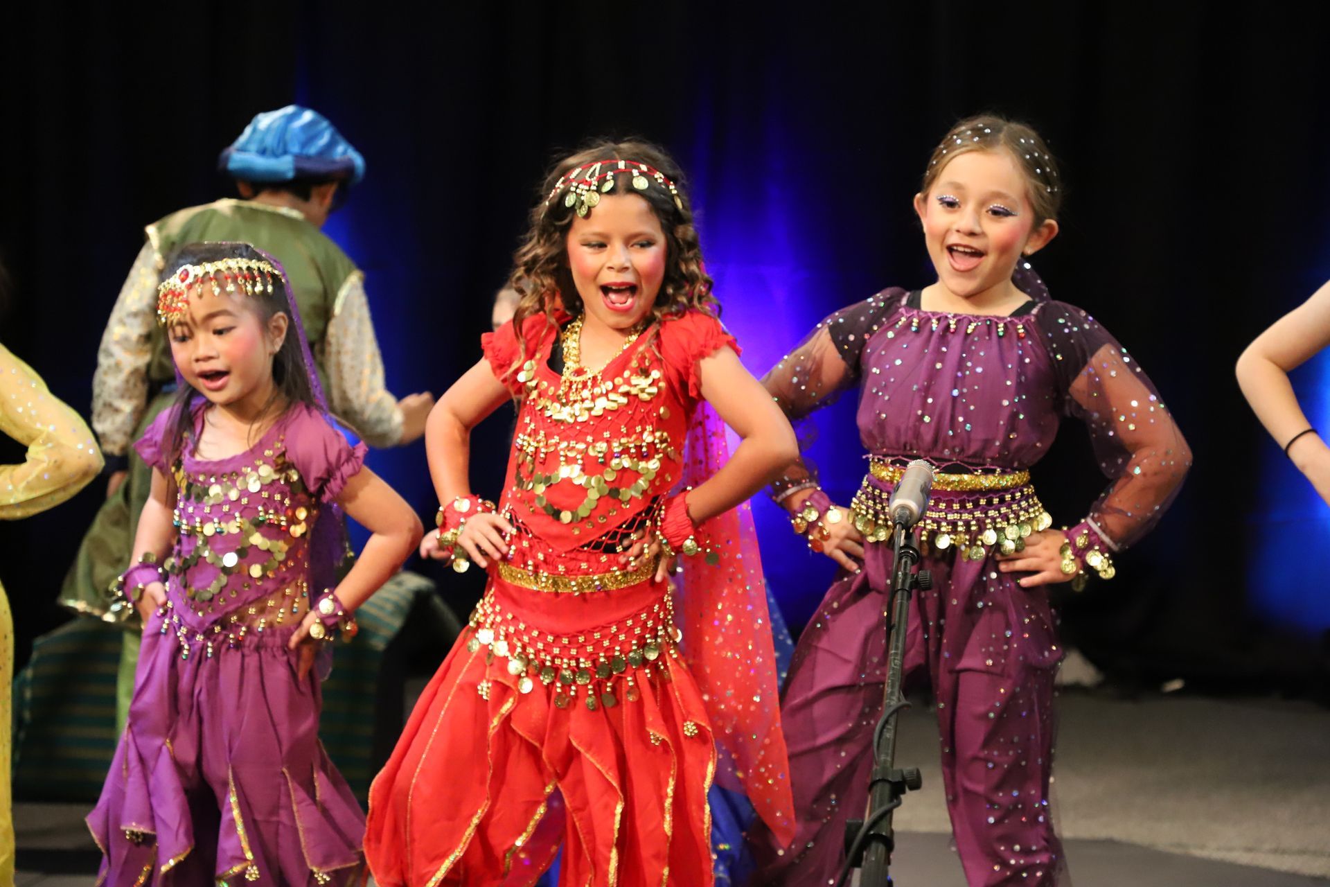 A group of young girls in costume are dancing on a stage