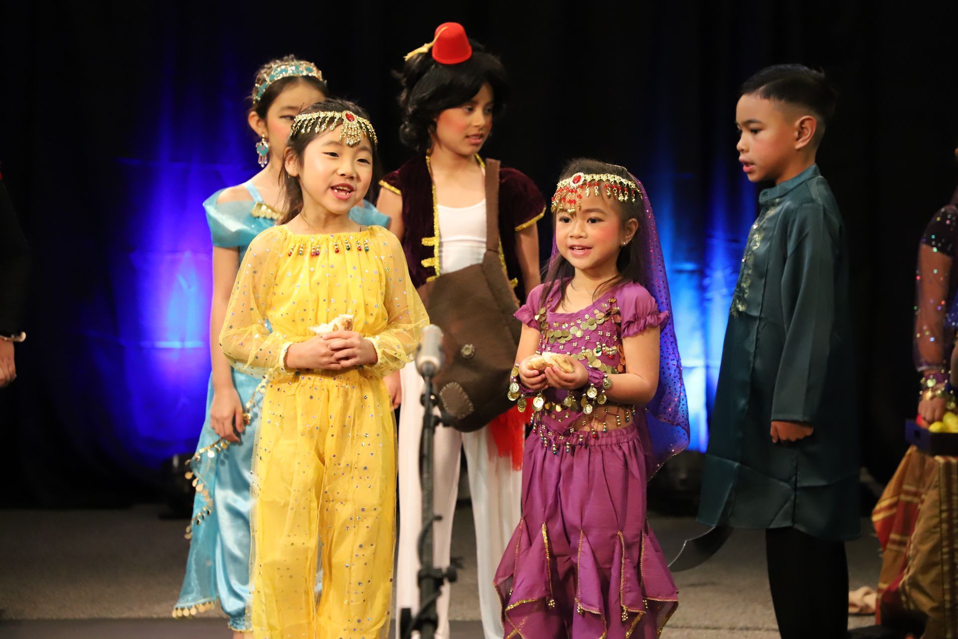 A group of children dressed in costumes are standing on a stage.