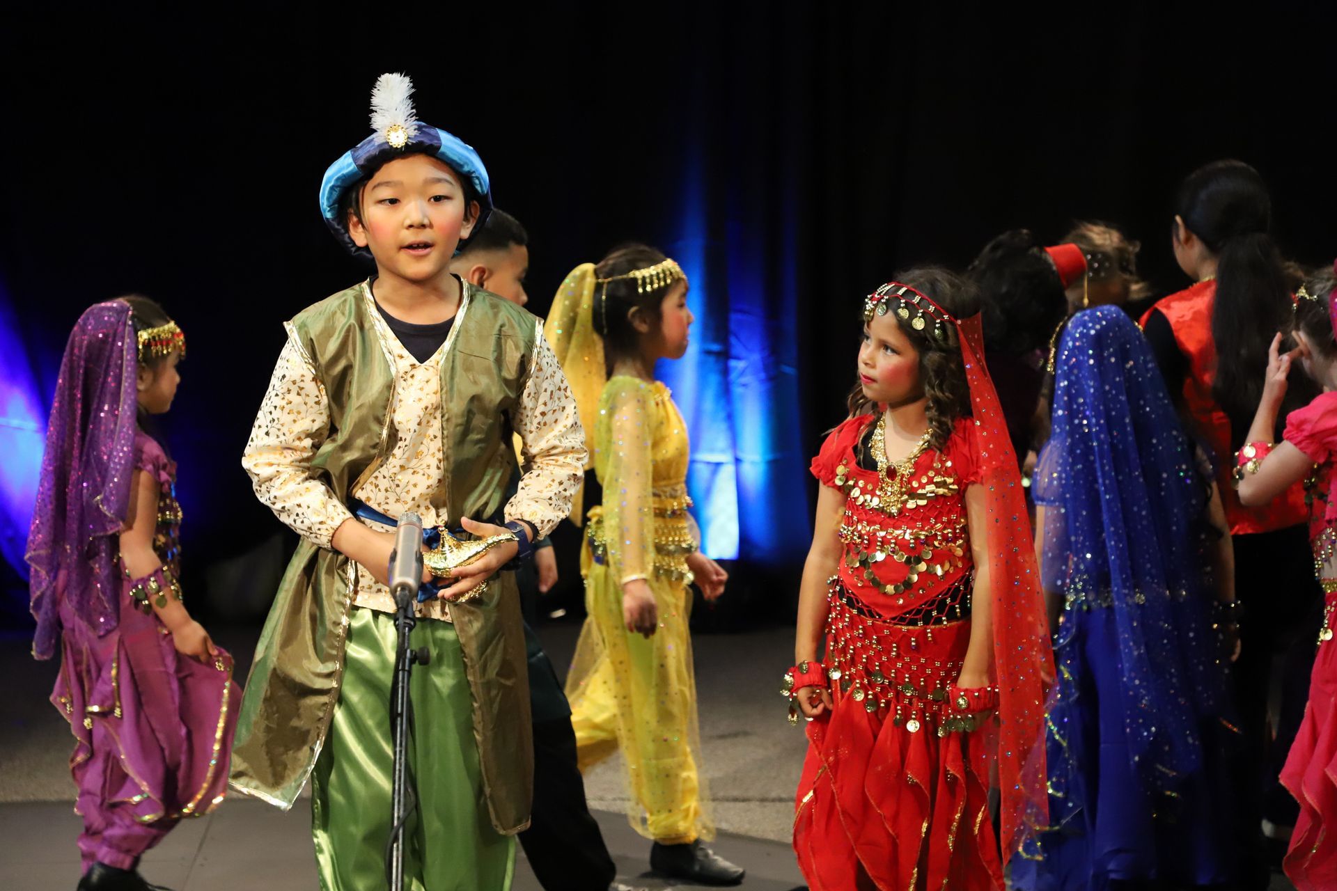A group of children dressed in costumes are standing on a stage.
