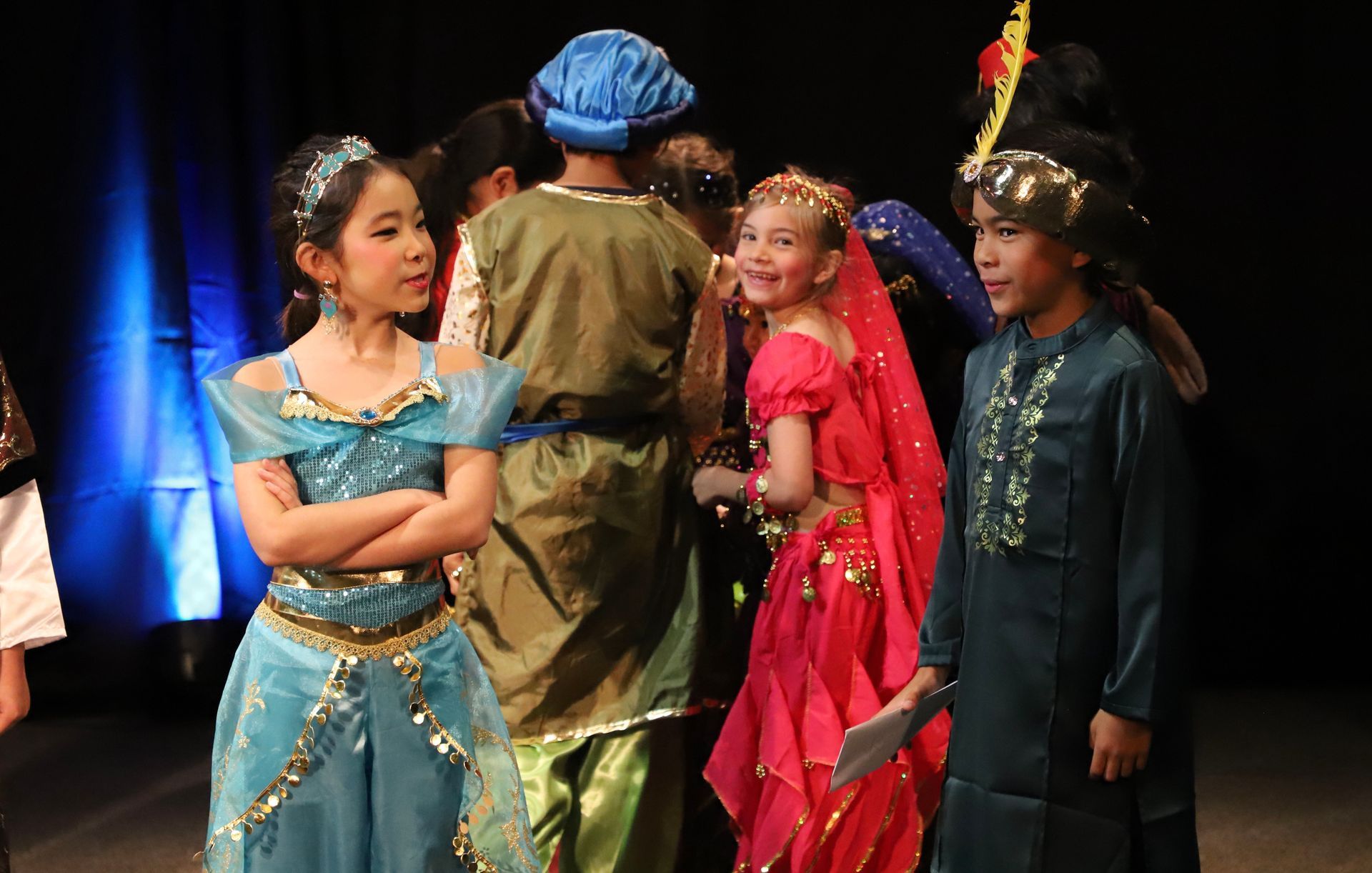 A group of children dressed in costumes are standing on a stage.