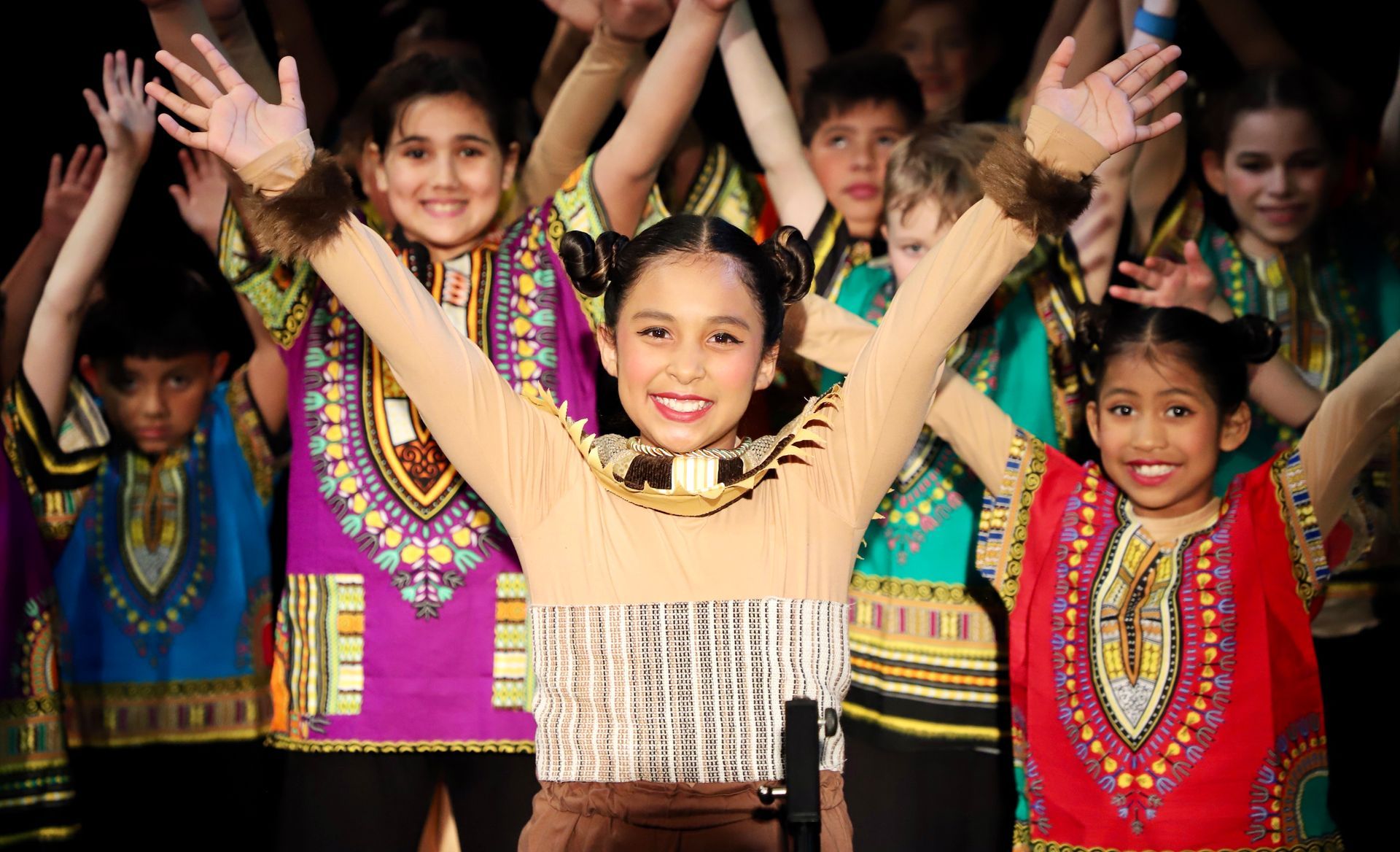 A group of children are dancing with their hands in the air.