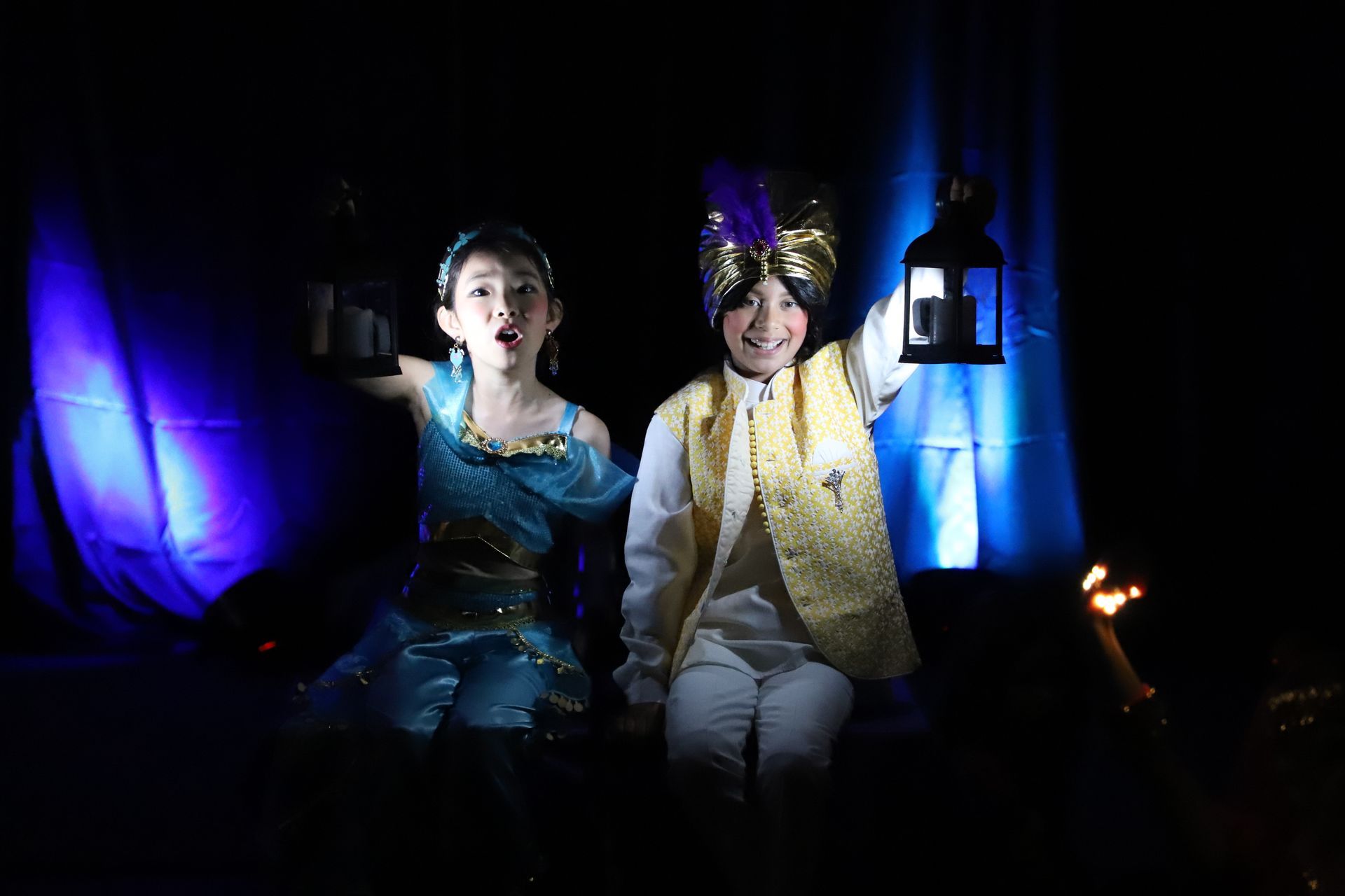 A boy and a girl in costumes are holding hands in the dark.