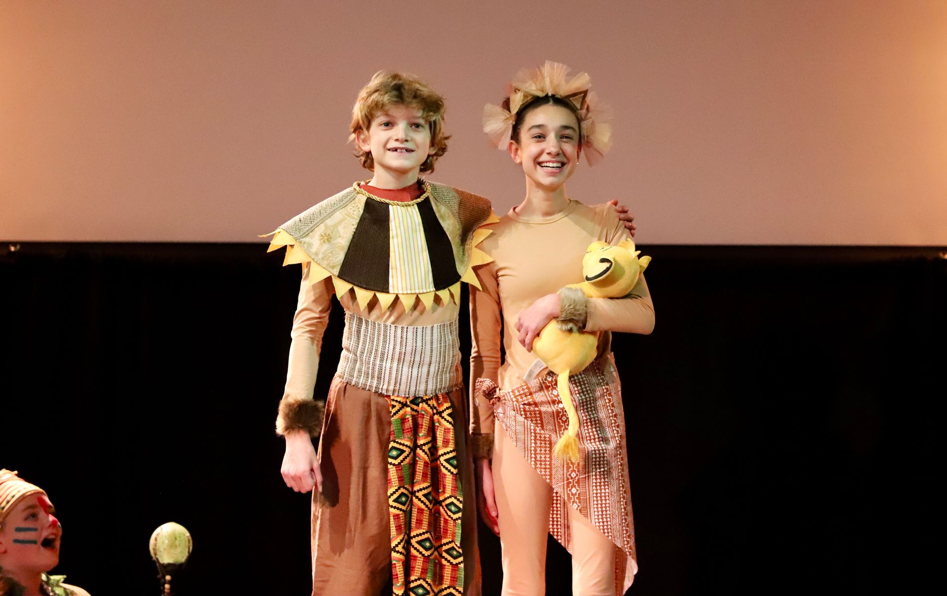 A boy and a girl in costume are standing next to each other on a stage.
