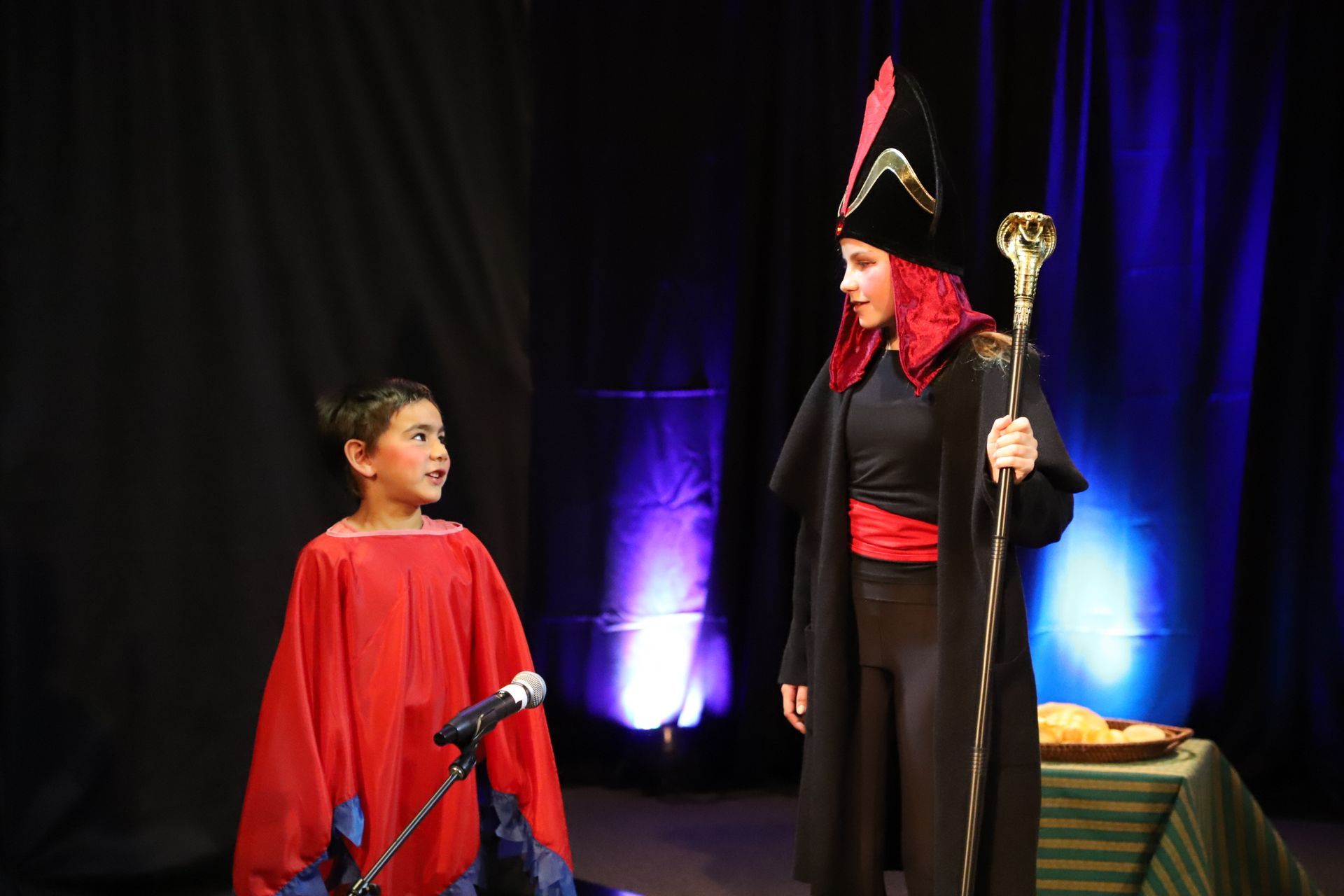 A woman in a costume is standing next to a boy in a red cape.