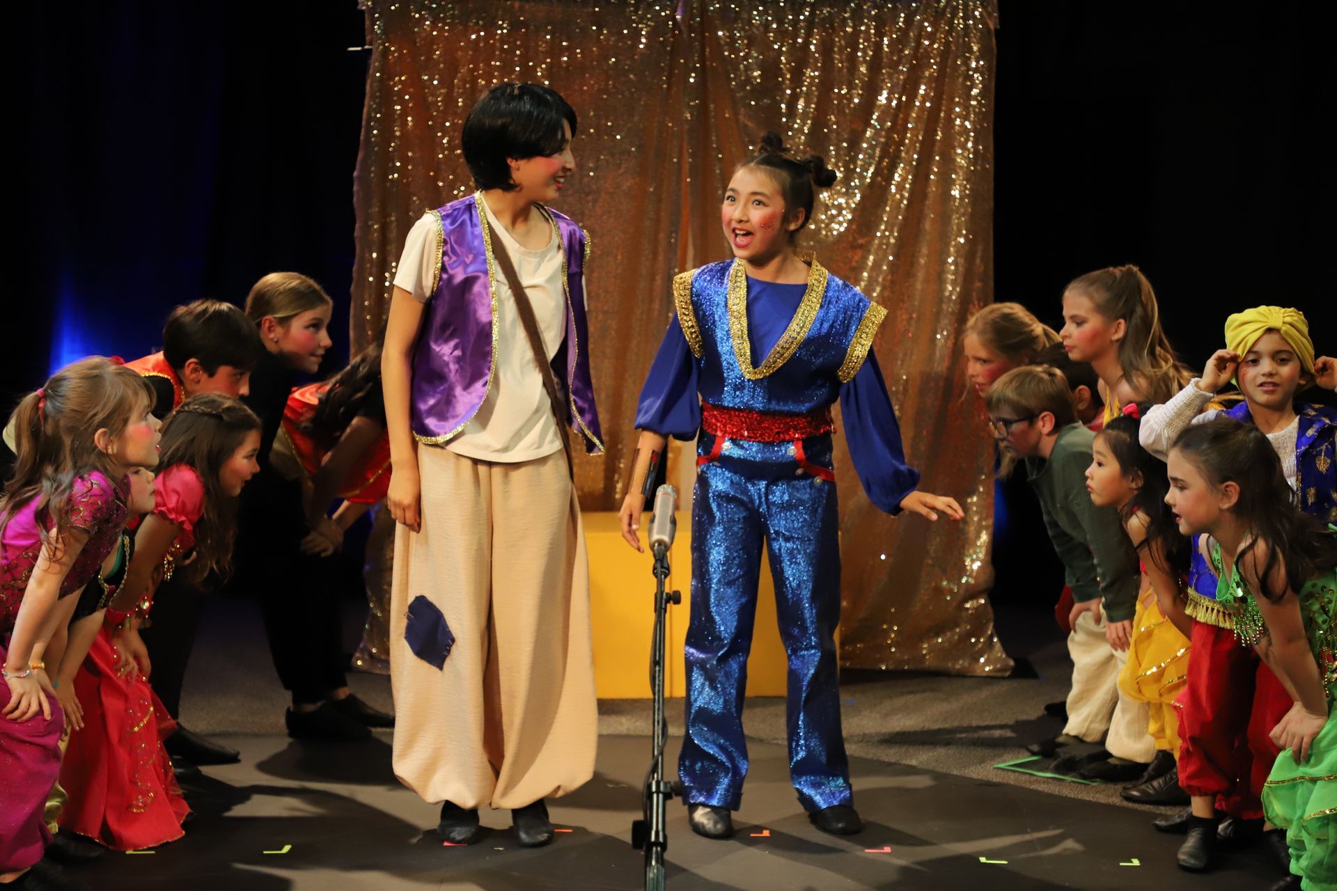 A group of children dressed in costumes are standing on a stage.
