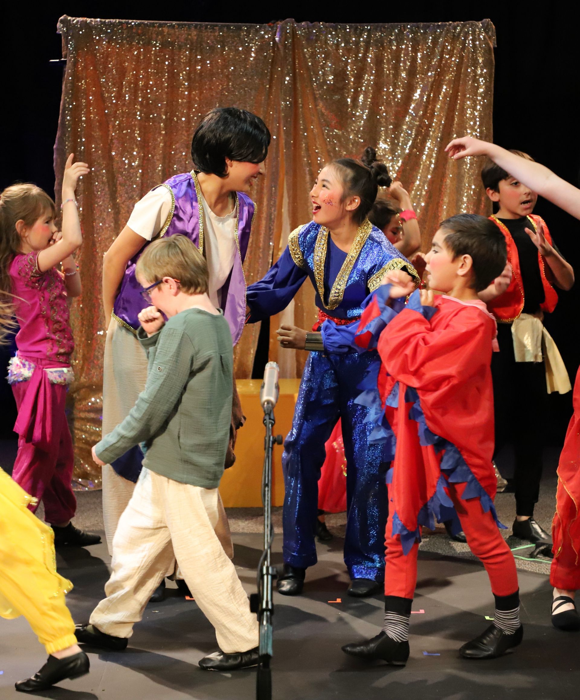 A group of children in costume are dancing on a stage