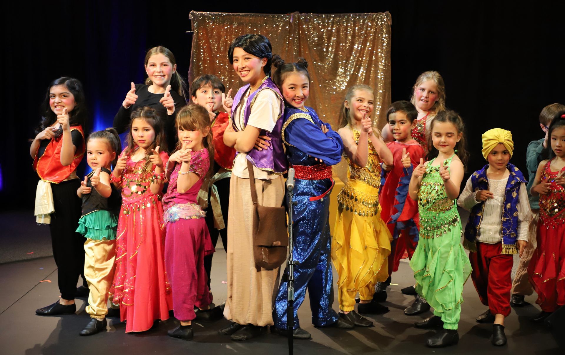 A group of children dressed in colorful costumes are standing on a stage.