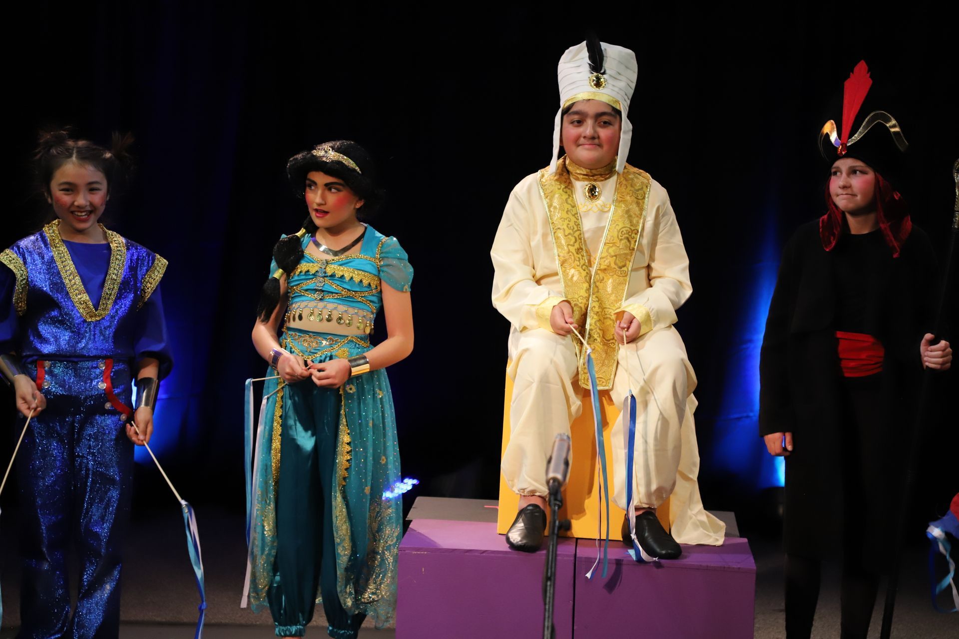 A group of children dressed in costumes are standing on a stage.