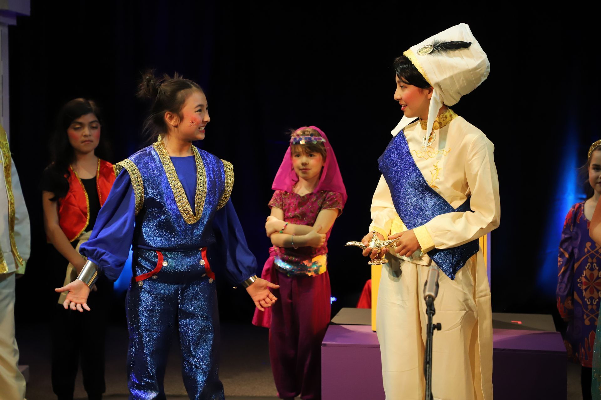 A group of people in costume are standing on a stage talking to each other.