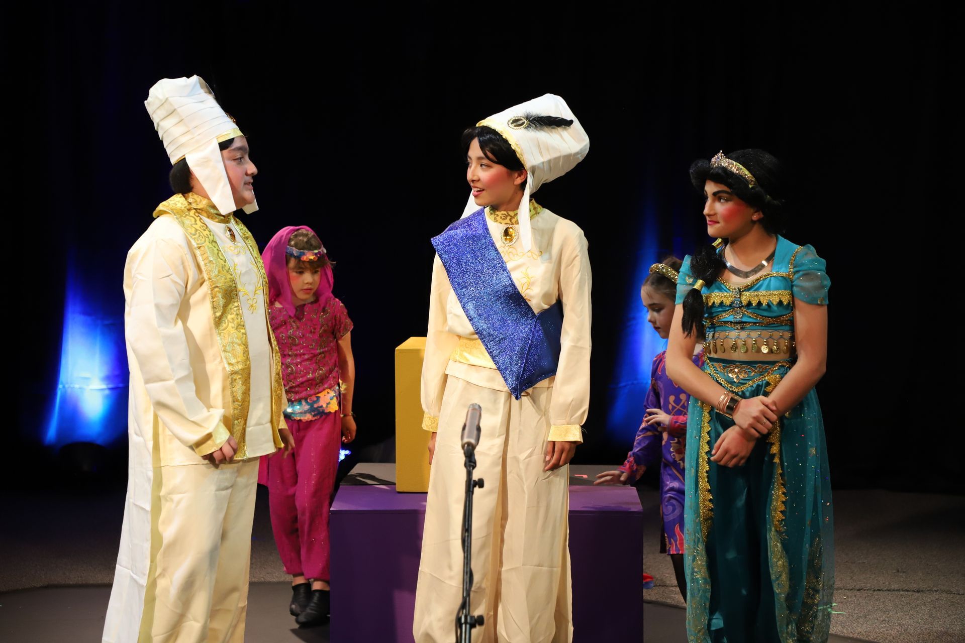 A group of people in costume are standing on a stage talking to each other.