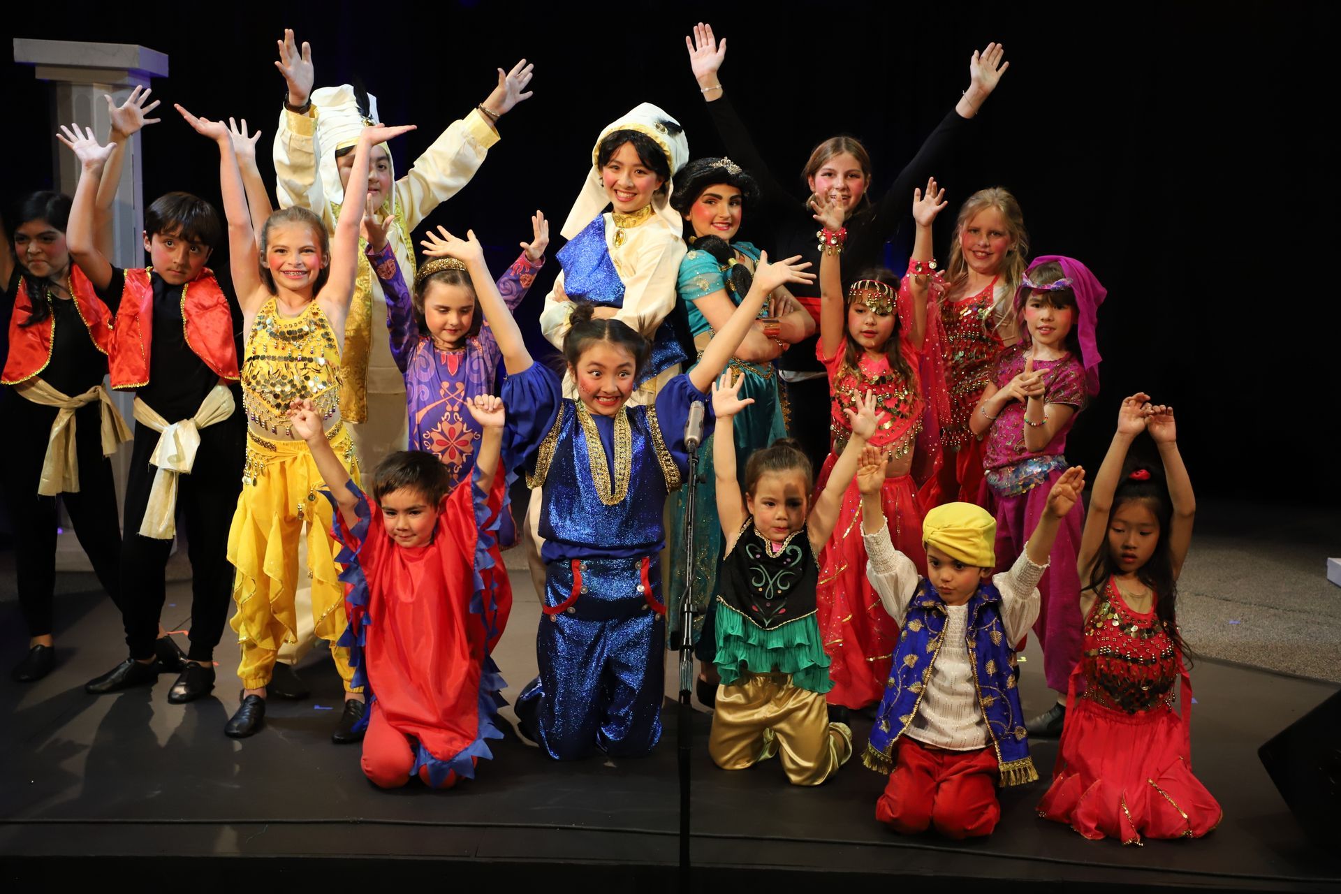 A group of children are posing for a picture with their hands in the air