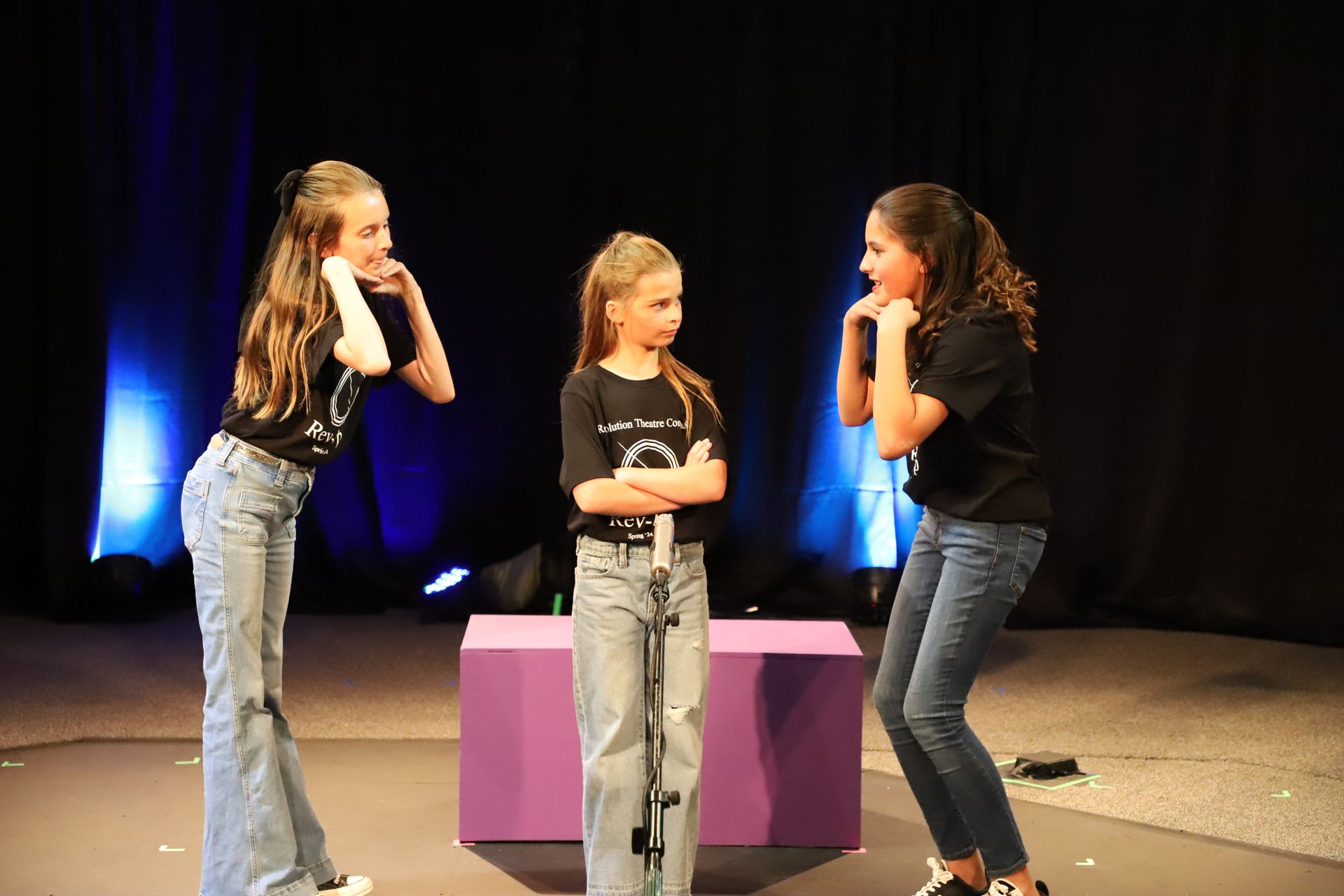 Three young girls are standing next to each other on a stage.