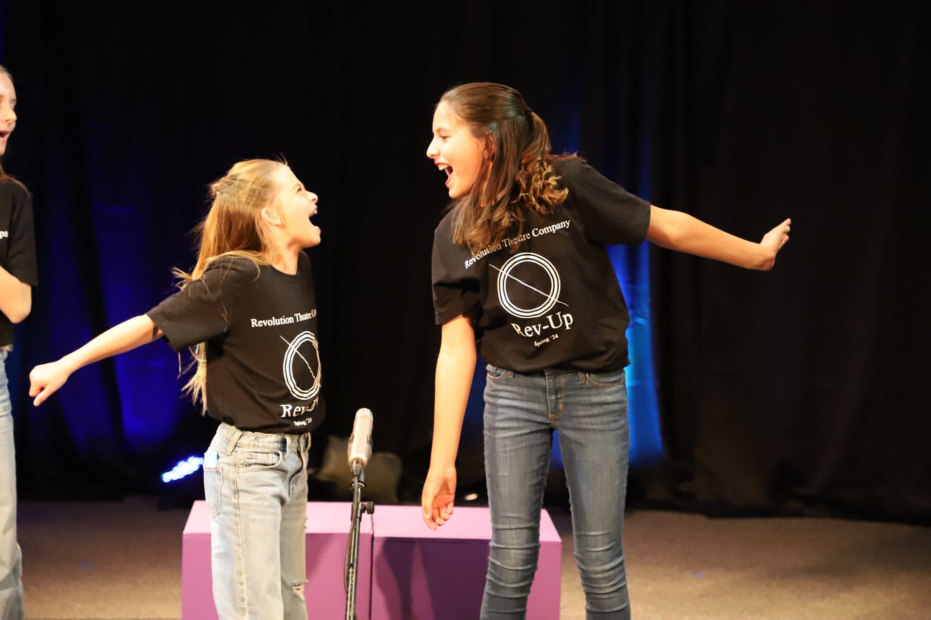 Two young girls are standing next to each other on a stage.