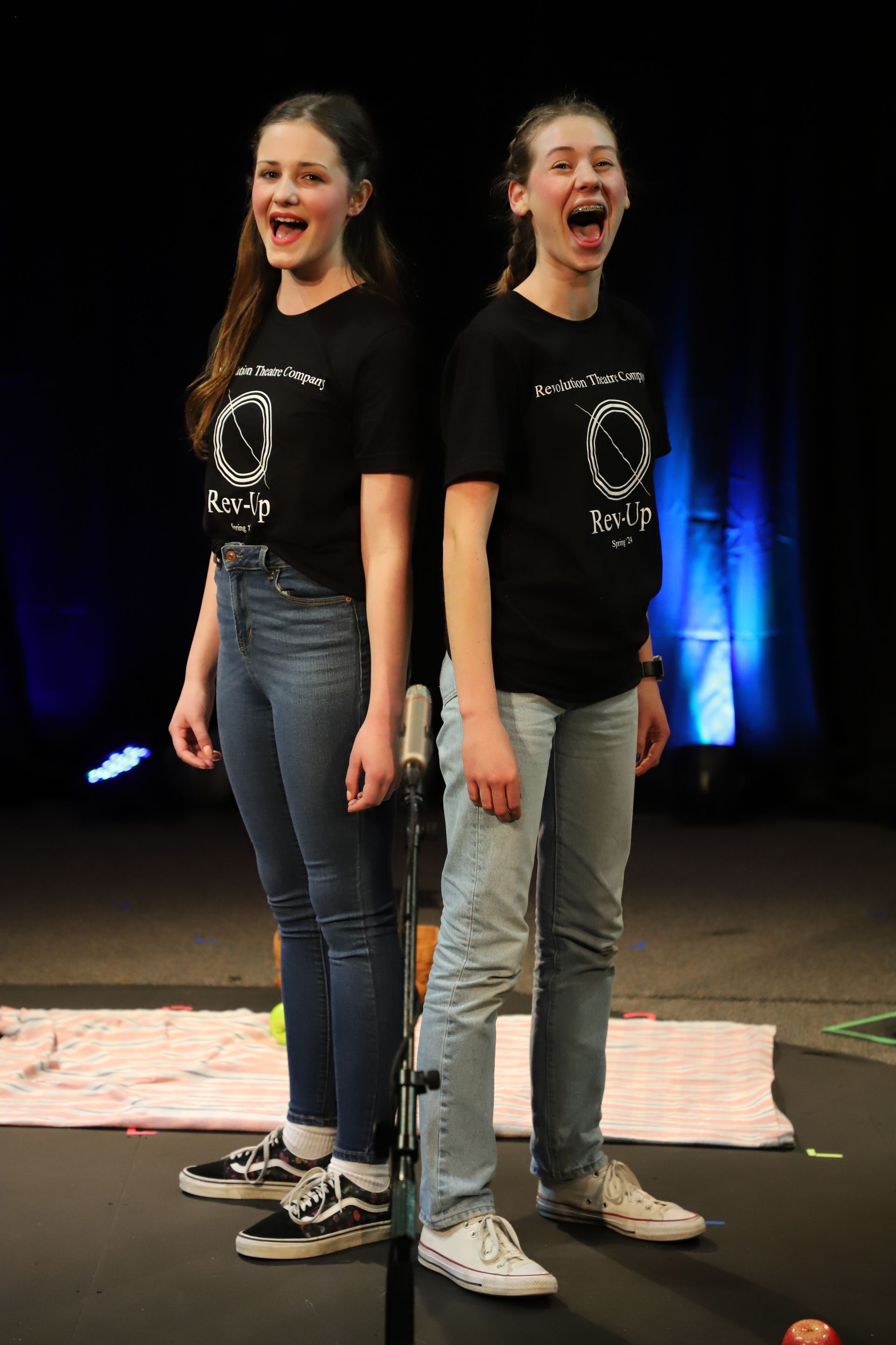 Two young girls are standing next to each other on a stage.